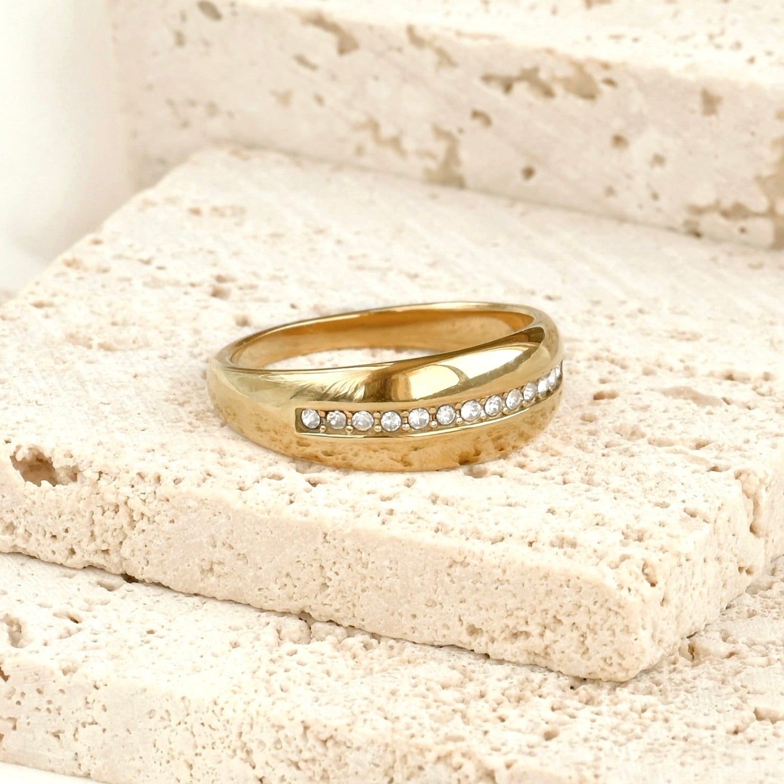 Thick gold ring with CZ line on a textured stone surface