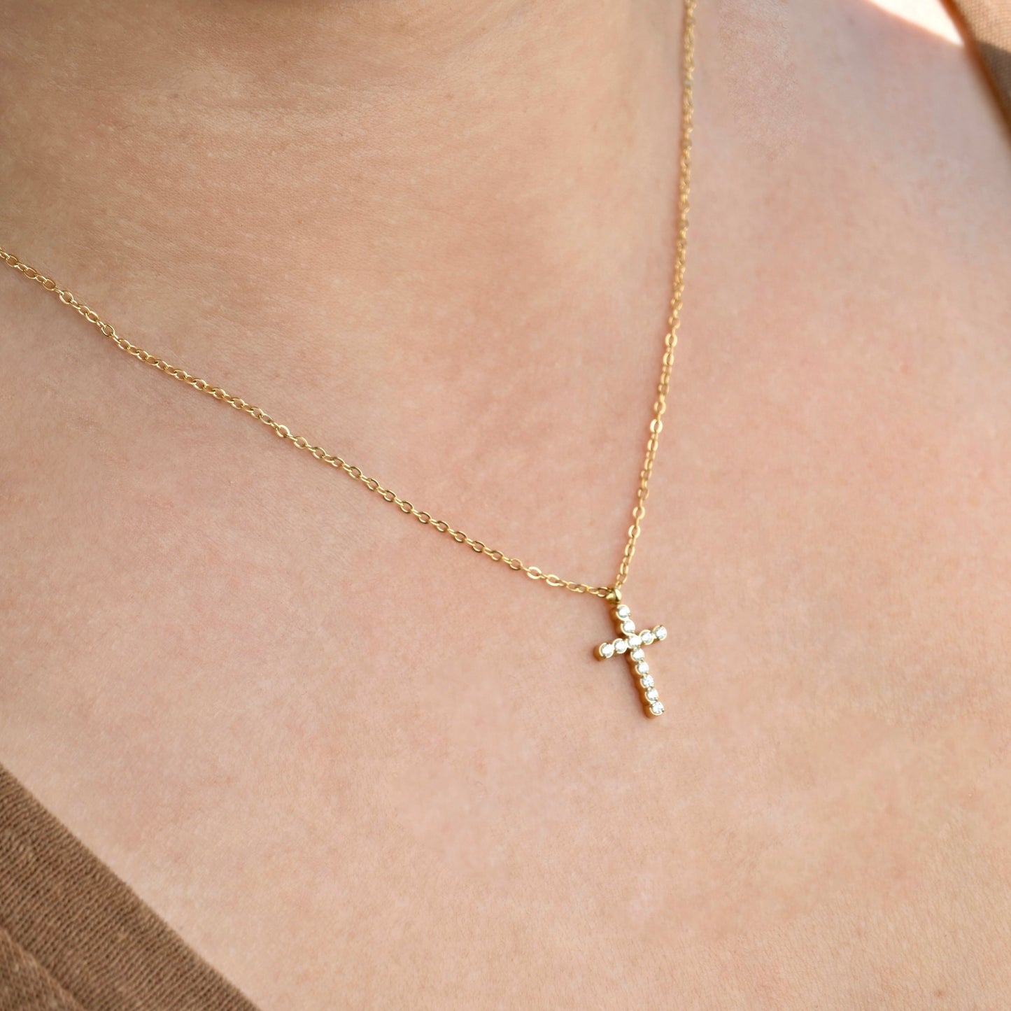Side view of gold necklace with a CZ cross pendant on a person's neck