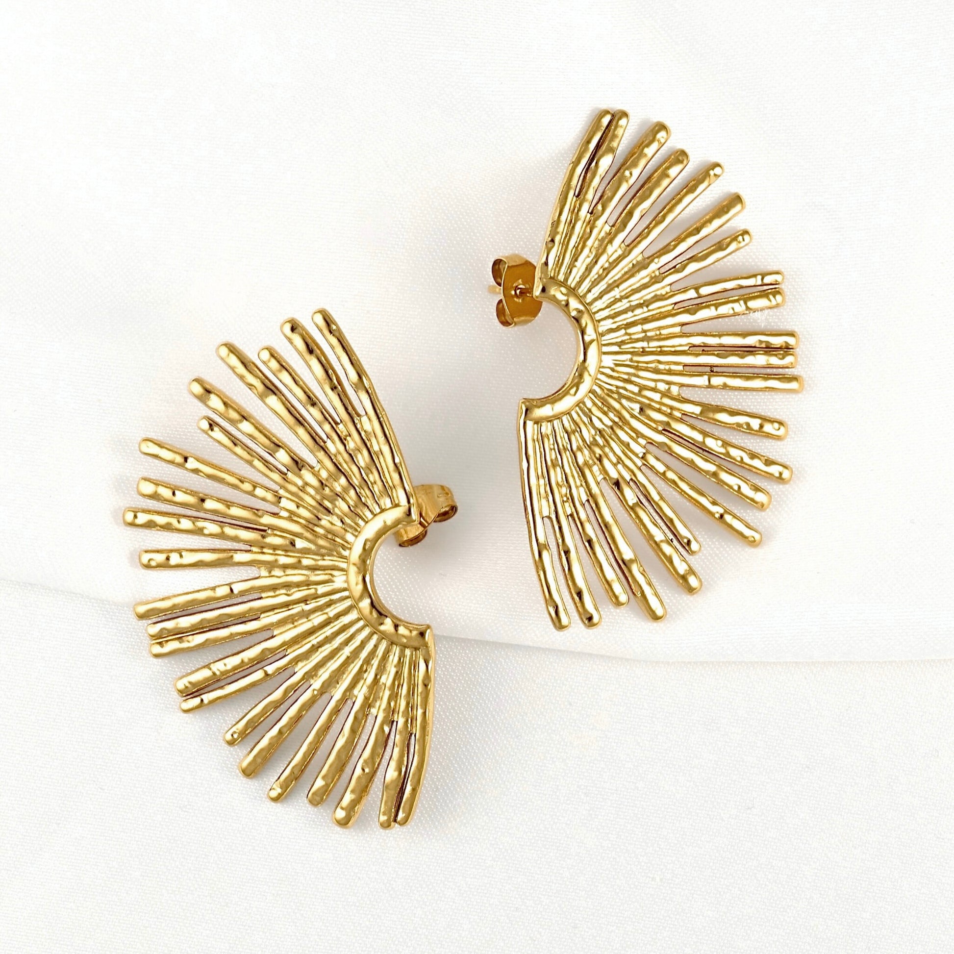 A pair of gold fan-shaped stud earrings with textured radiating bars, displayed on a clean white background.