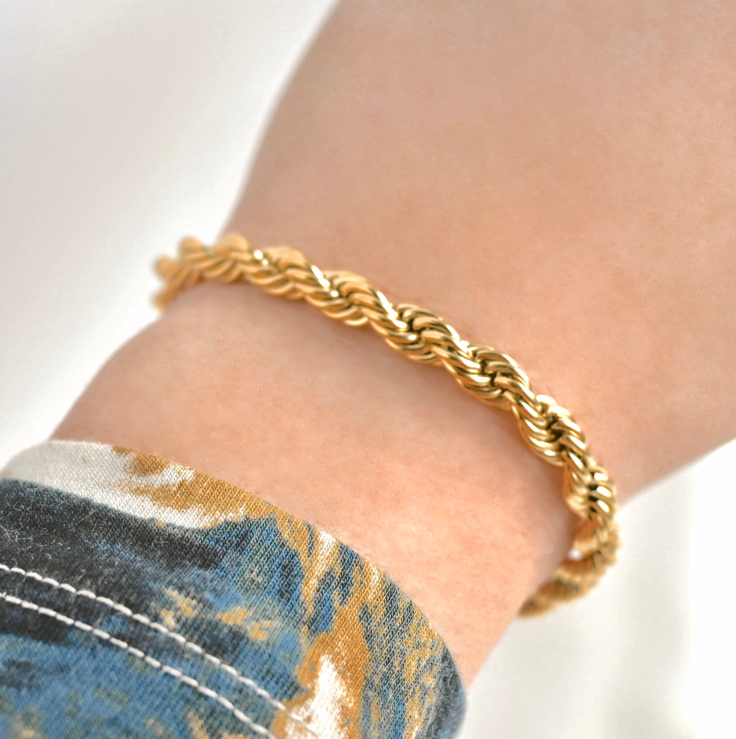 Gold braided bracelet on a wrist with a blurred background