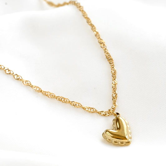 Gold heart pendant necklace on a white background