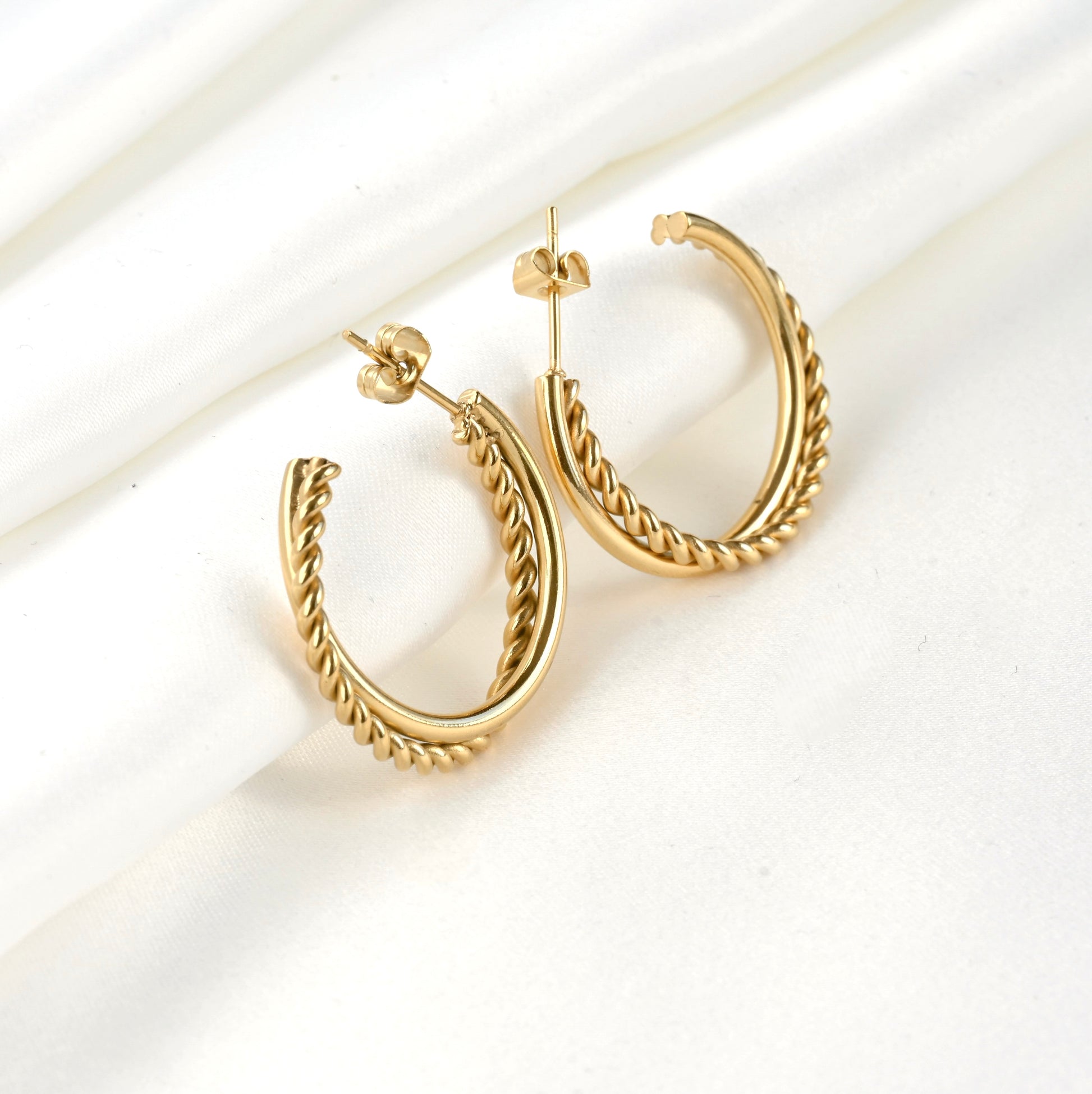 Gold twisted hoop earrings on a white background