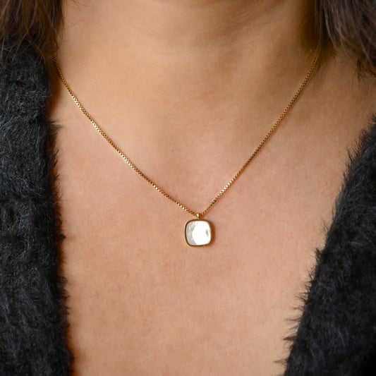 Gold box chain necklace with a  shell inlay square pendant worn by a person