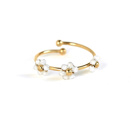 A gold-plated open cuff ring decorated with three small white flower clusters, each featuring a gold center and clear faceted beads, set against a plain white background.