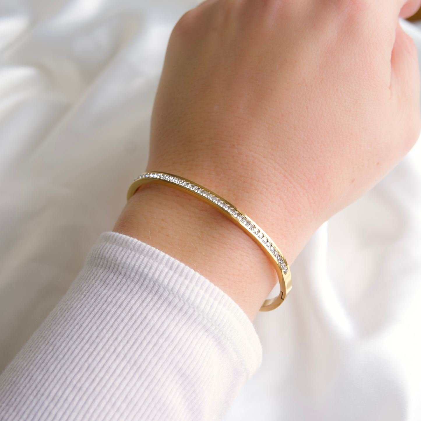 Gold bangle bracelet on a wrist with a blurred background