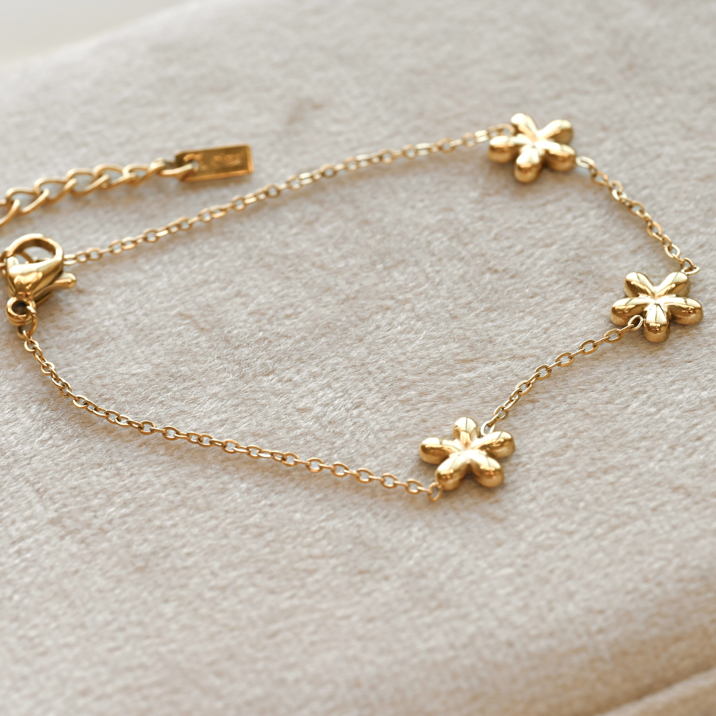 Gold bracelet with floral charms on a light gray background