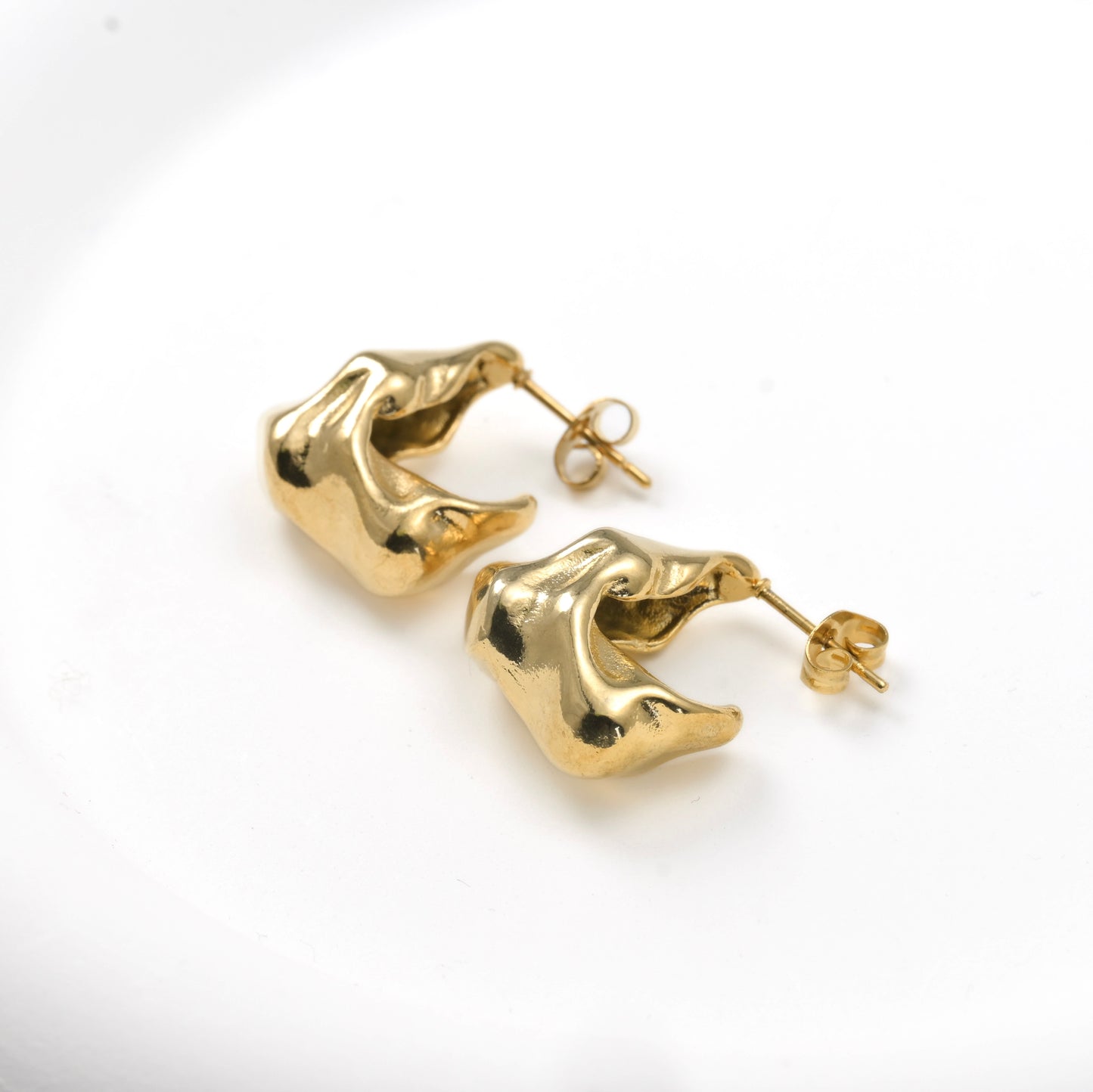 Gold abstract earrings on a white background