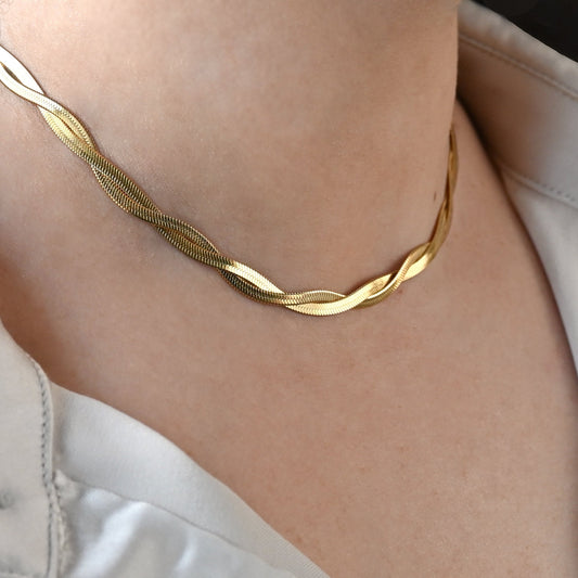 Gold  braided herringbone necklace on a person wearing a white shirt