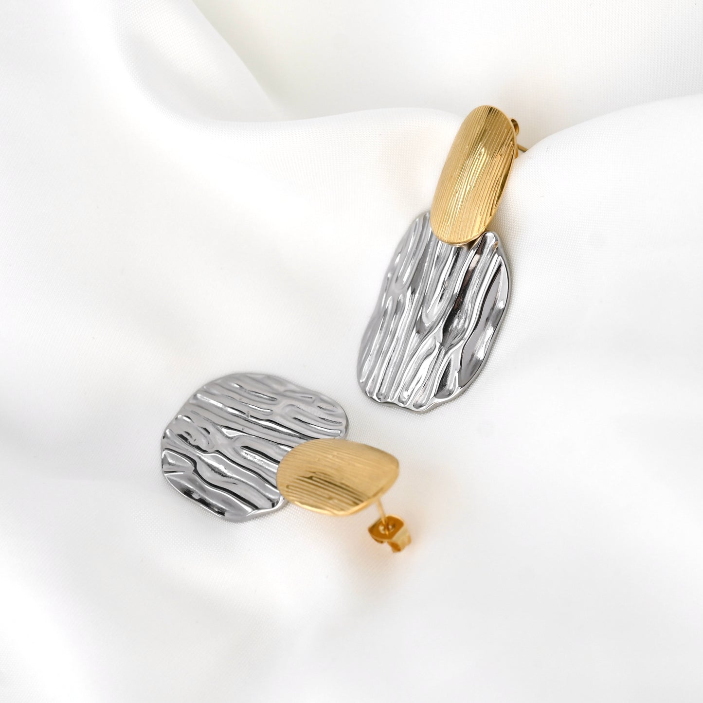 Pair of earrings with two-tone textured design on a white background