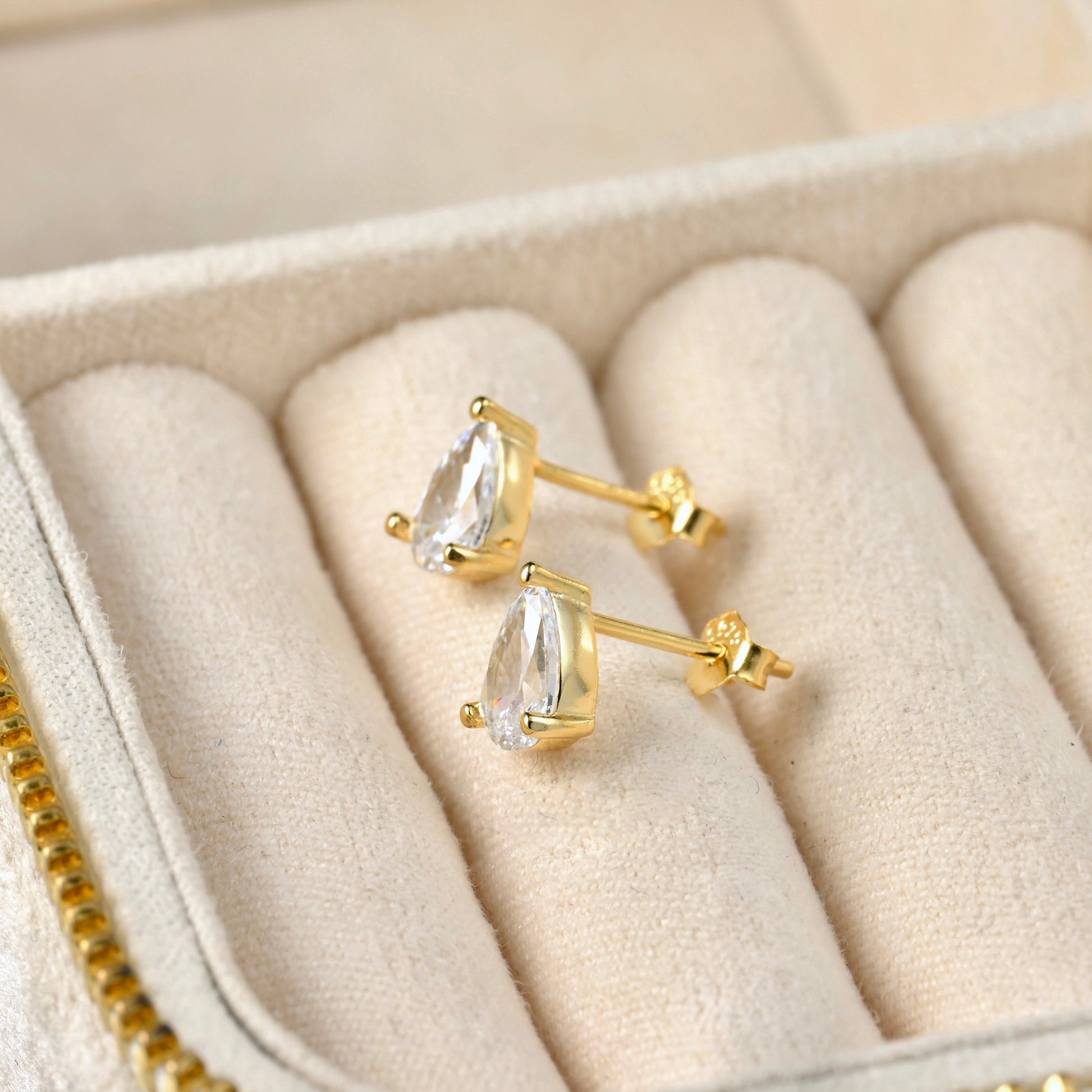 Gold earrings with clear pear-cut gemstones in a jewelry box