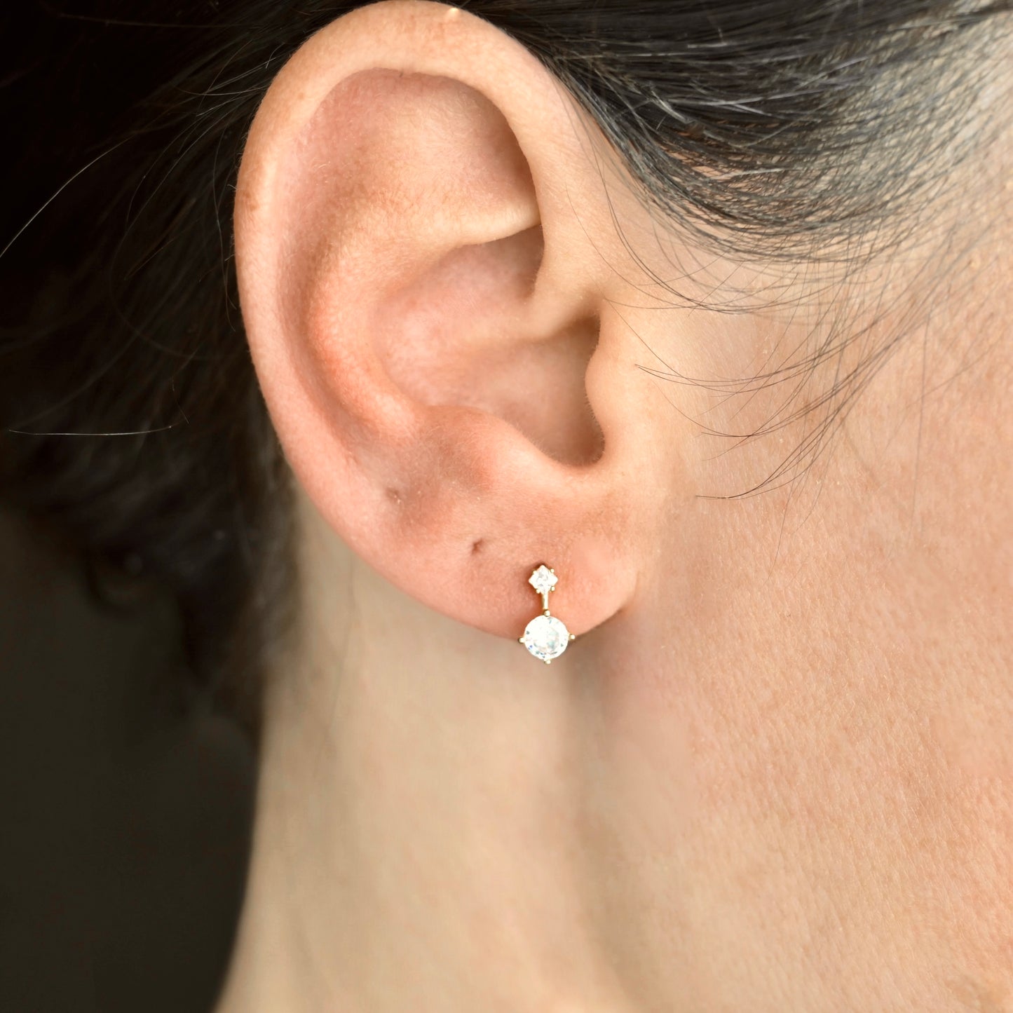 Close-up of an ear wearing a diamond earring with a blurred background