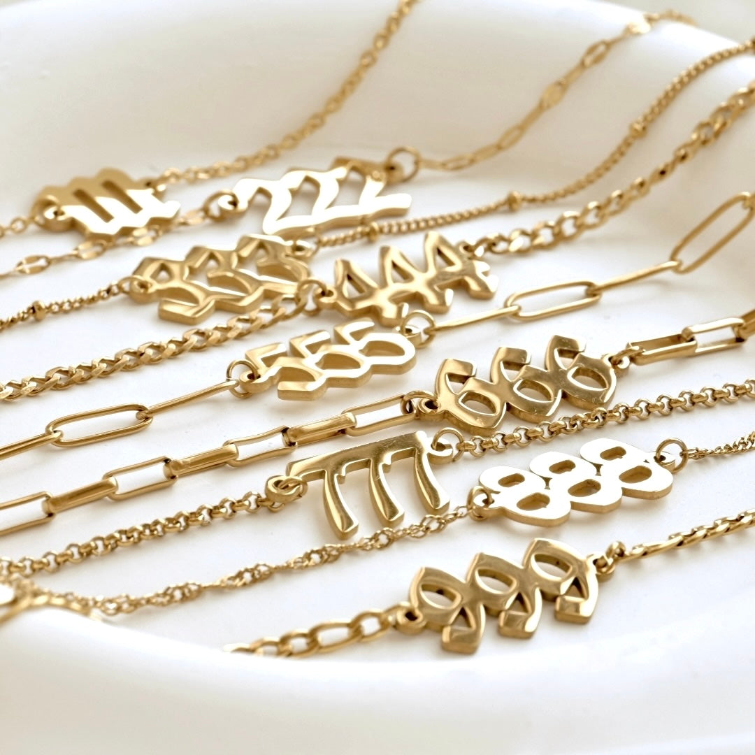 Gold necklaces with various number designs on a white surface