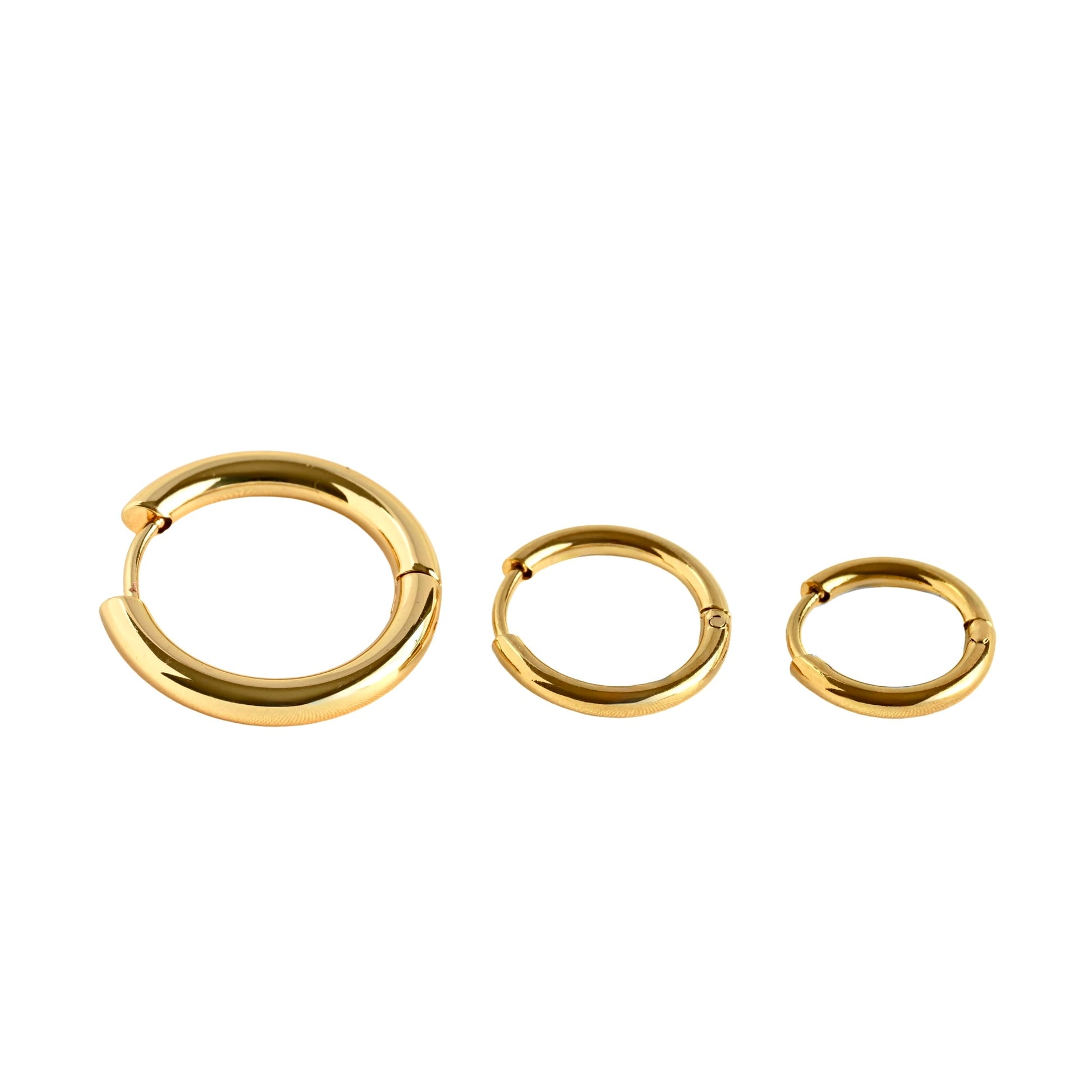 Close-up view of subtle gold hoop earrings set in small medium and large sizes on a white background