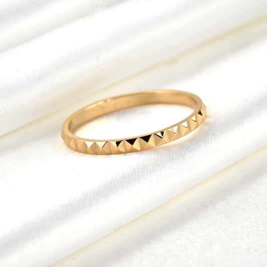 Gold ring with pyramid texture on a white fabric background