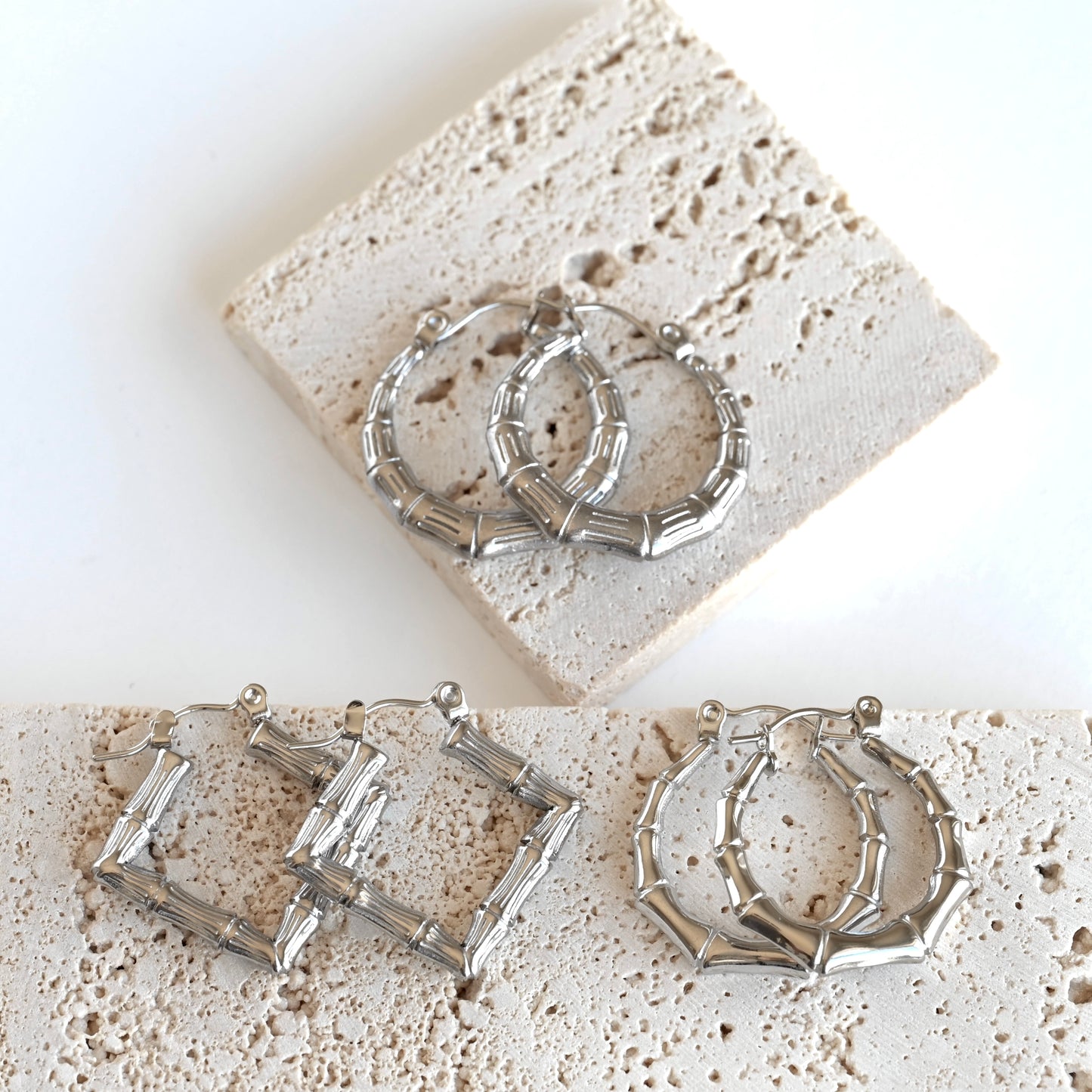 Three pairs of silver-toned hoop earrings with a textured, segmented geometric design, displayed on a white background with light beige stone tiles.