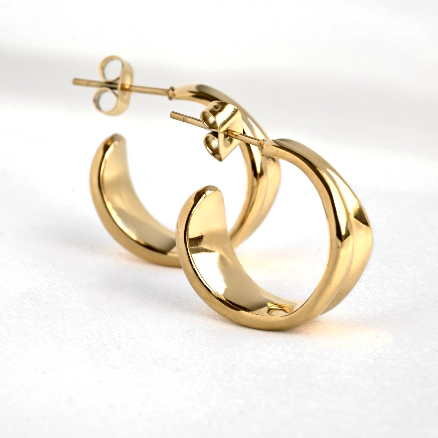 Medium sized gold C hoop earrings on a white background