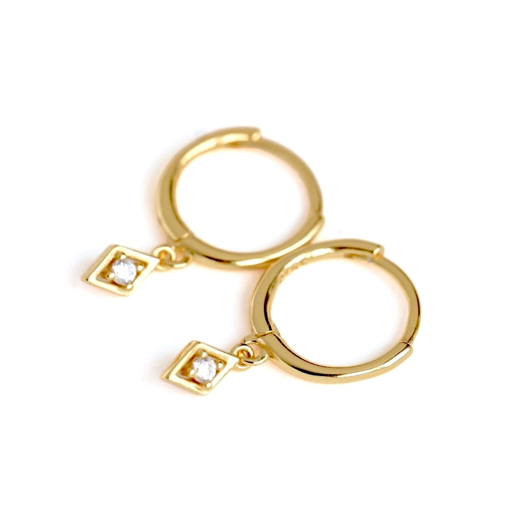 A pair of gold huggie hoop earrings with small round clear  CZ stones, shown on a plain white background.