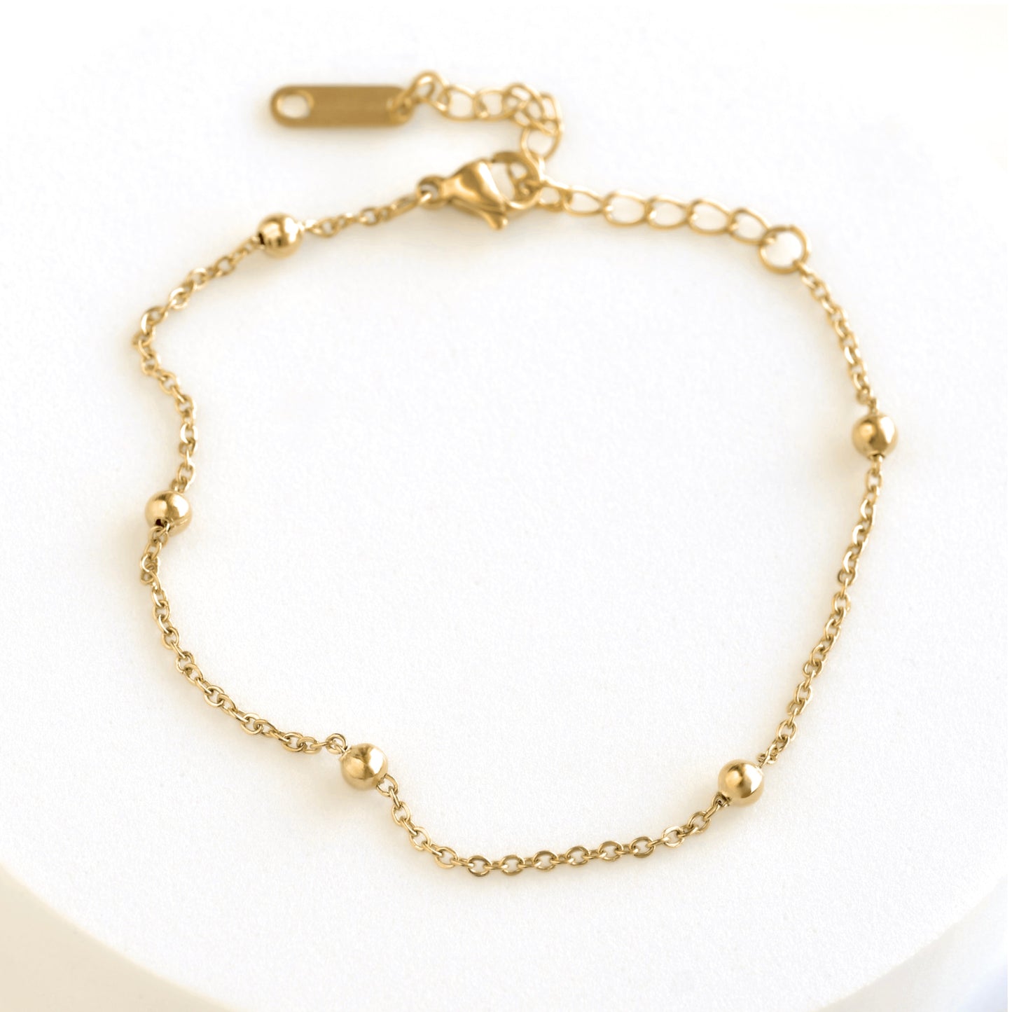 A delicate gold chain bracelet with small ball stations and an adjustable lobster clasp, displayed on a clean white background.