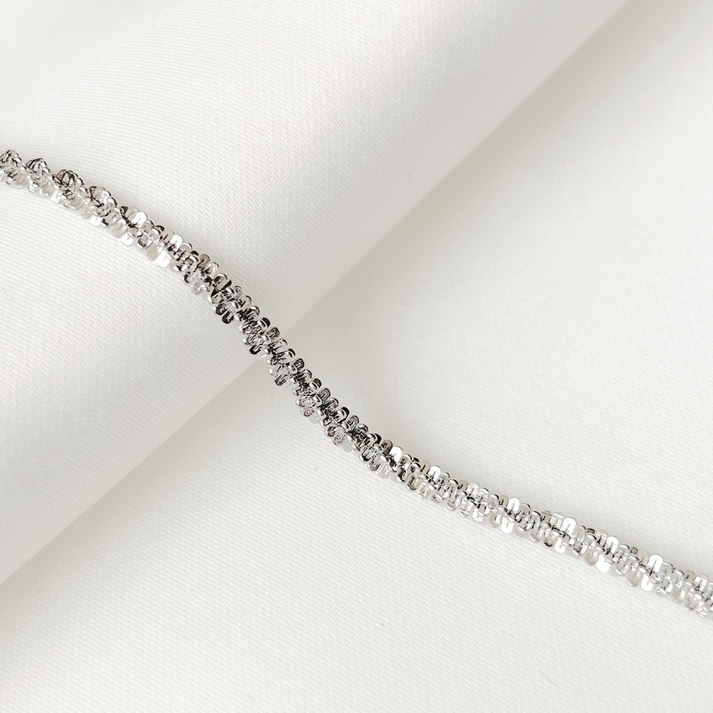 Unique silver chain bracelet with twisted links sparkling like gemstones on a white background