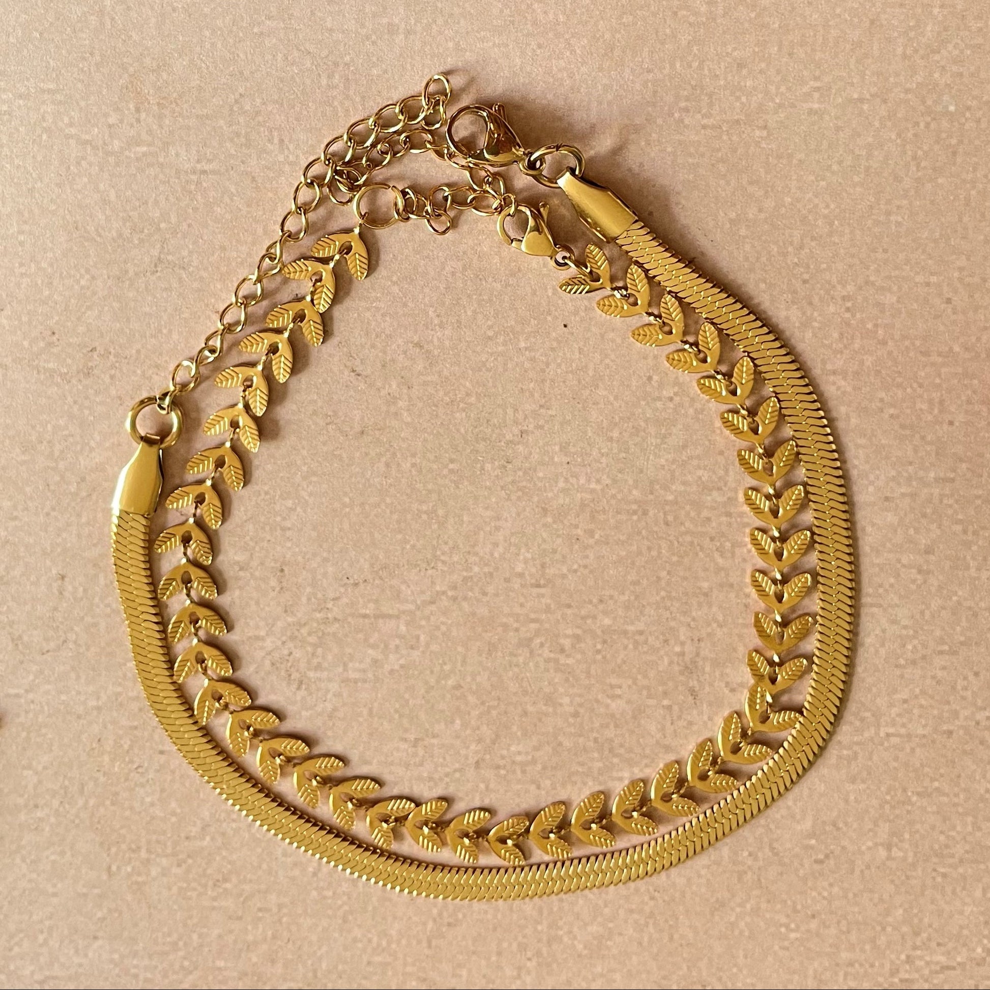 Gold chain necklace on a beige surface with seashells and a starfish.