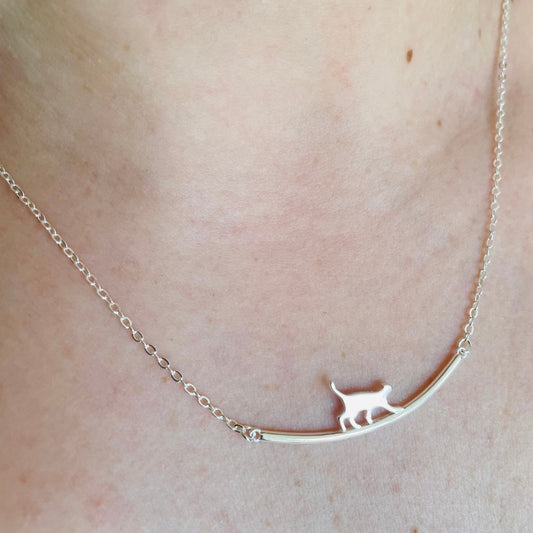 Silver necklace with a cat pendant on a person's neck