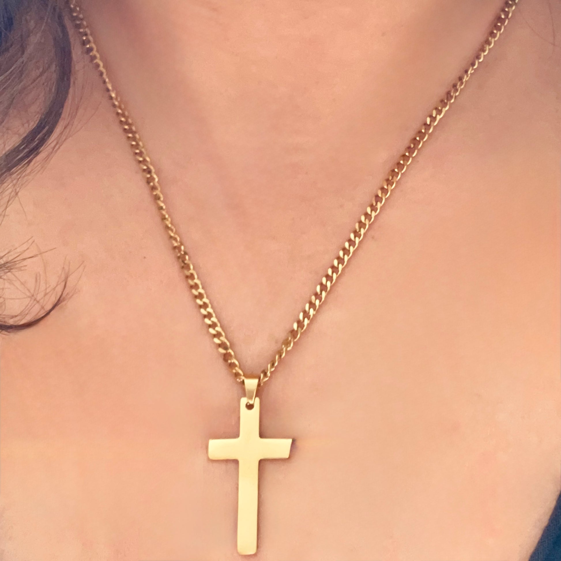 Front view of a woman wearing a gold cross necklace on a 3mm cuban chain 