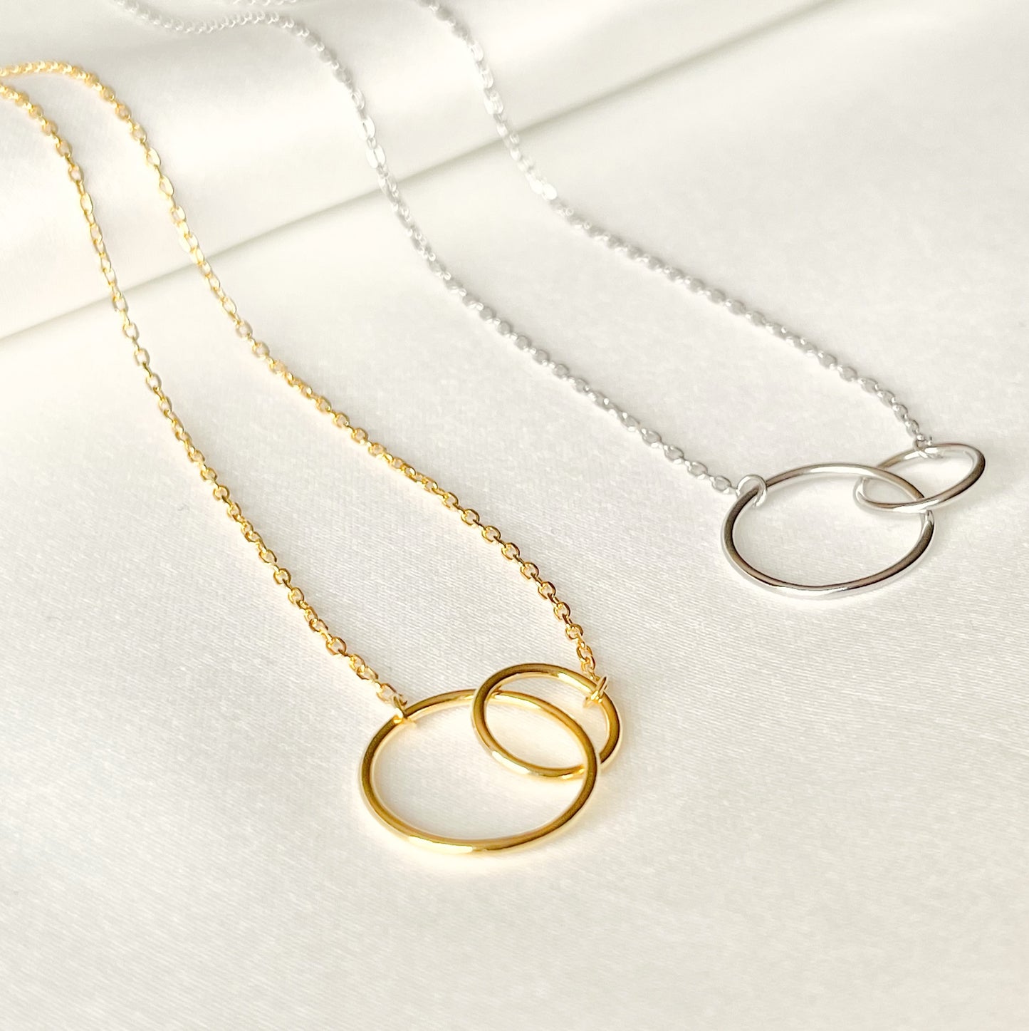 Gold and silver necklaces with circular designs on a white background