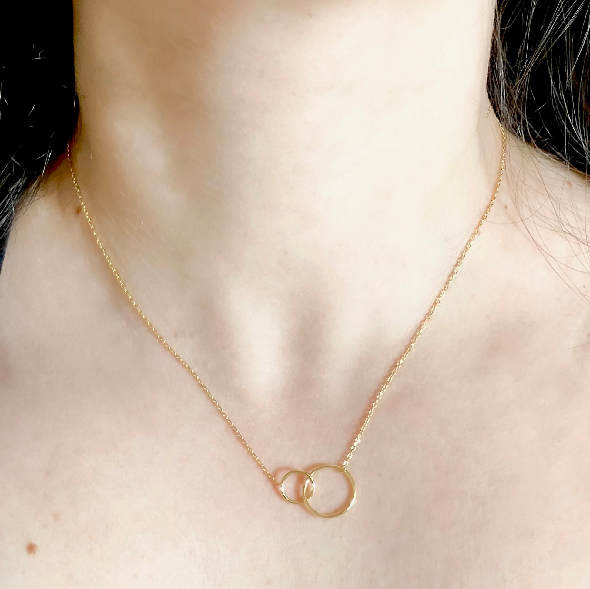Gold necklace with interlocking rings on a person's neck