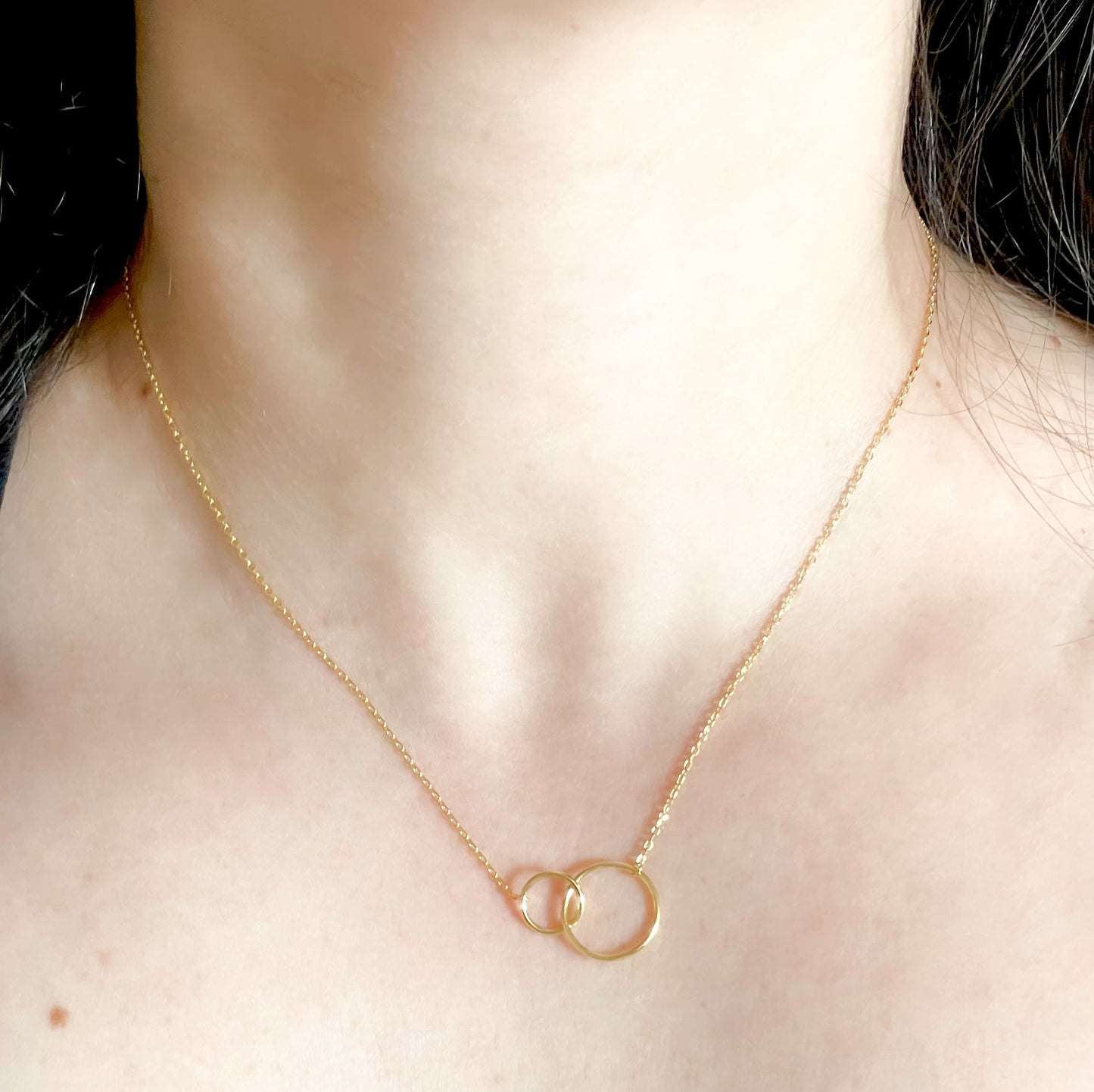 Gold necklace with interlocking rings worn by a person