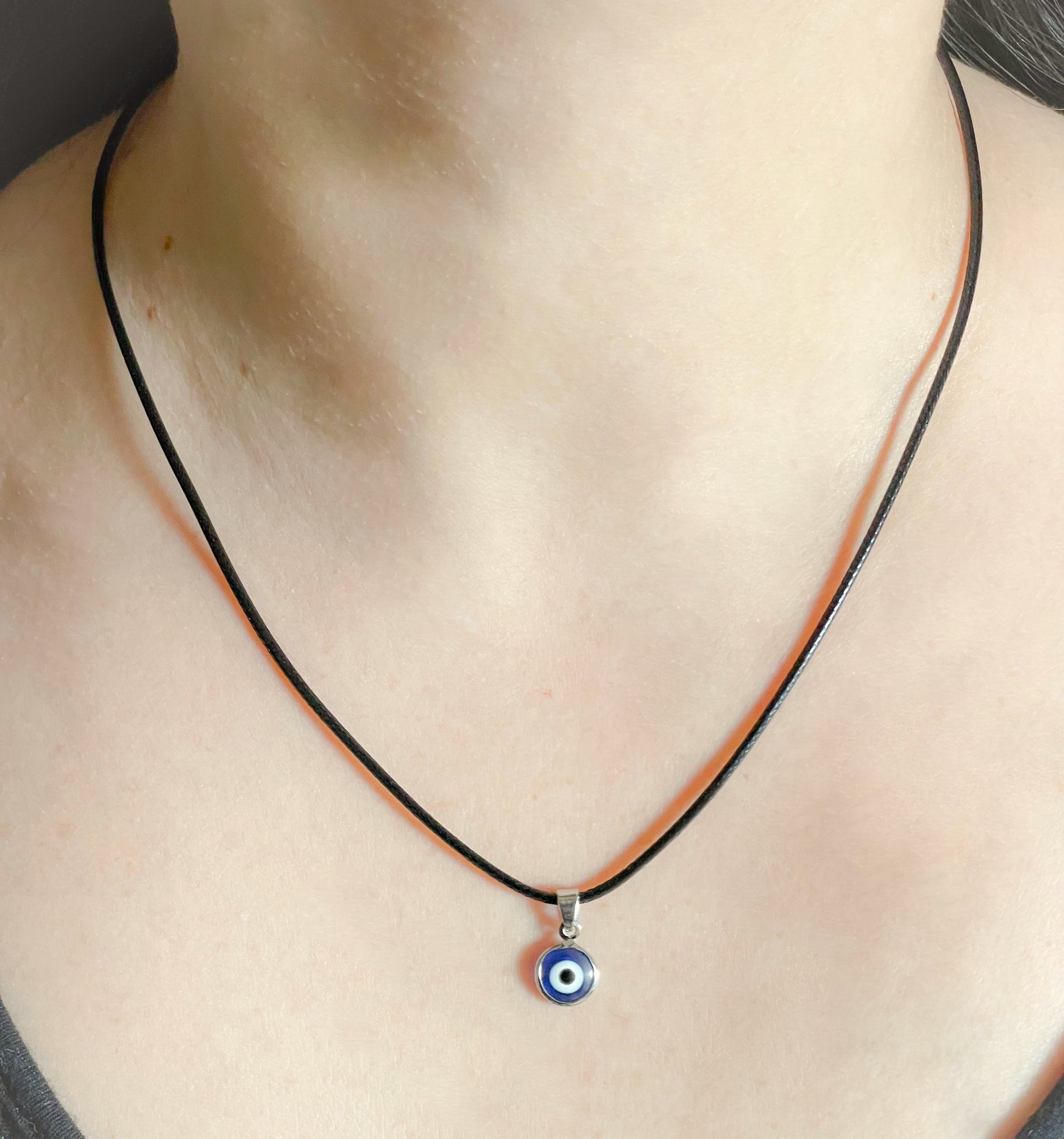 Black Rope necklace with a small blue evil eye pendant on a woman's neck