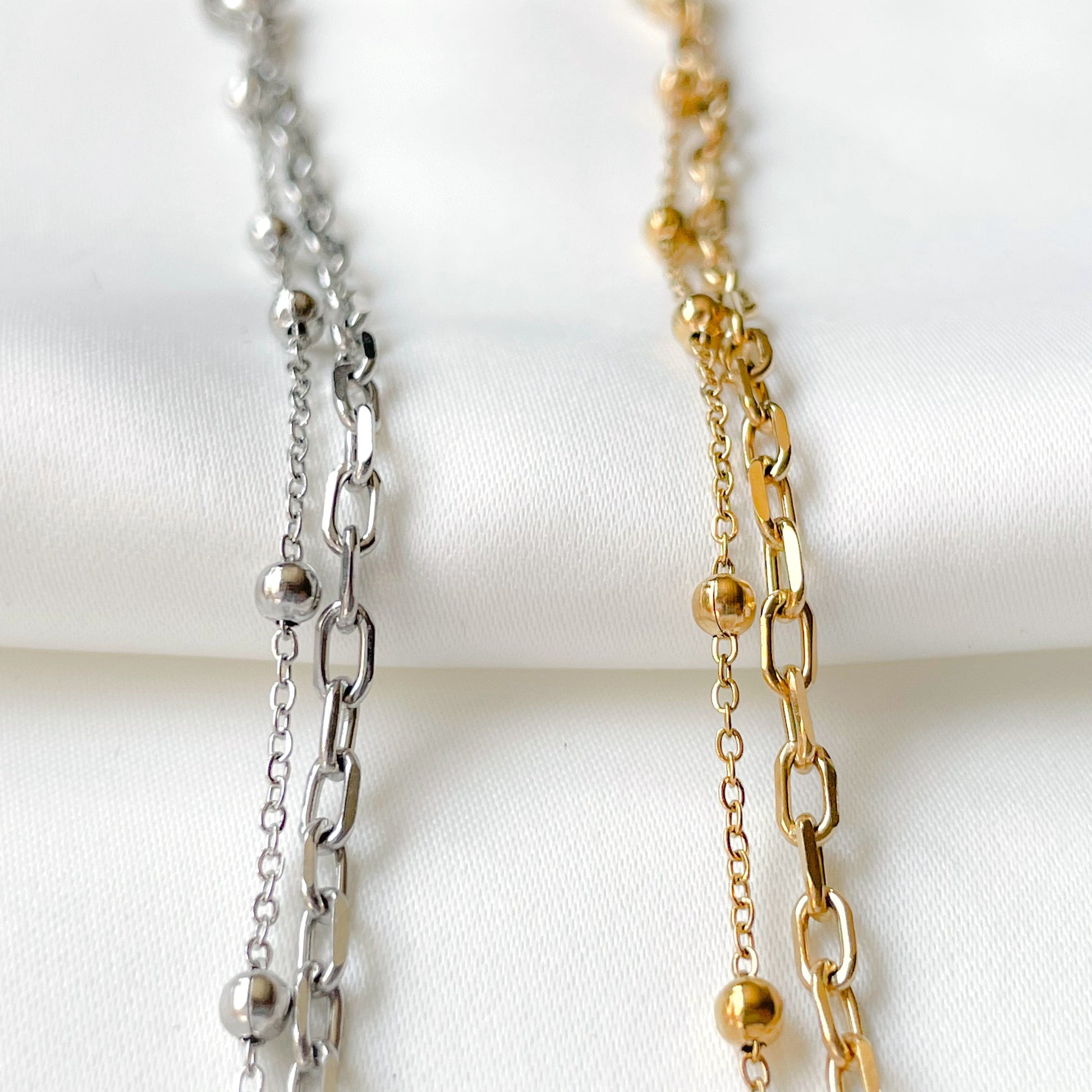 Two gold and silver chain bracelets on a white background