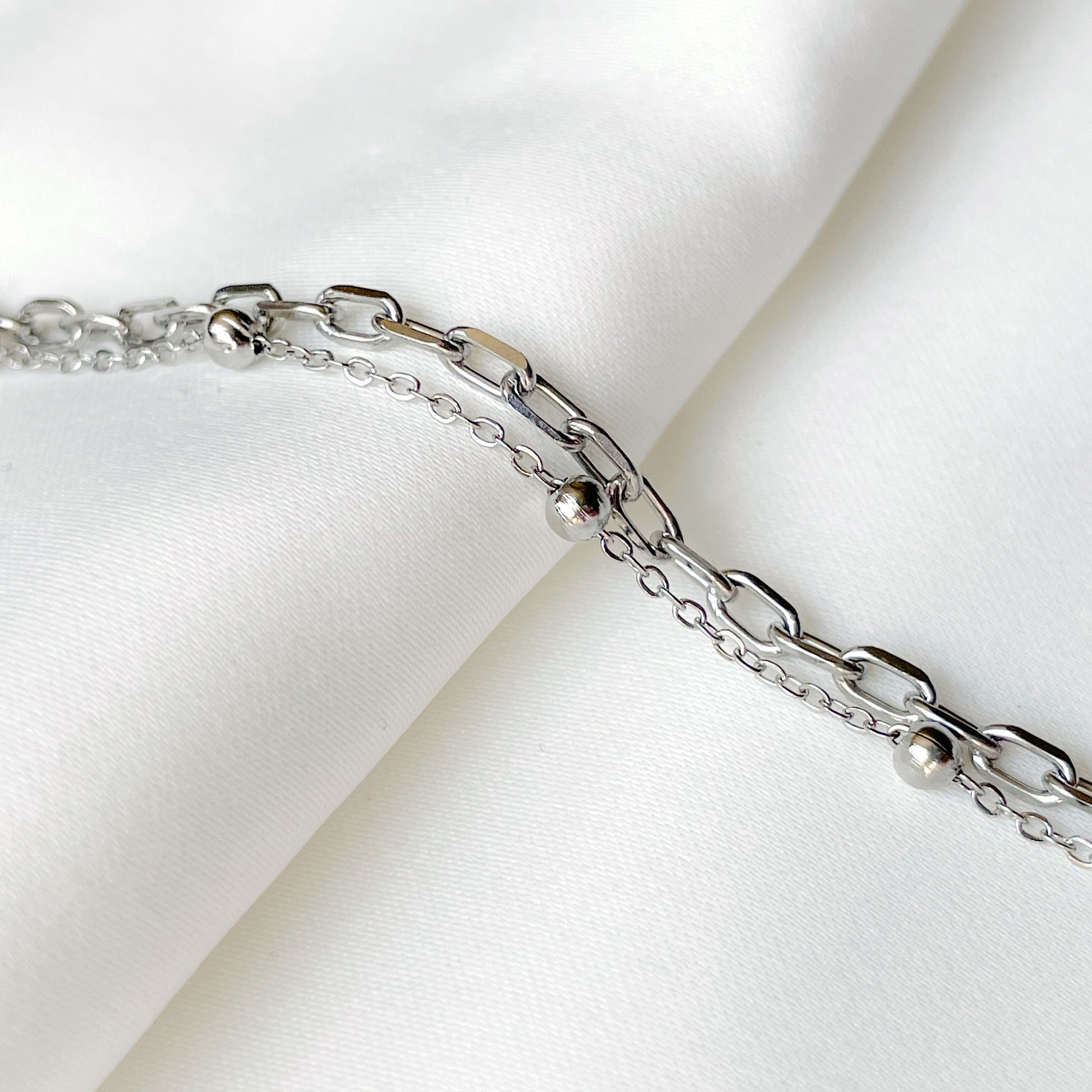 Silver chain bracelet on a white fabric background