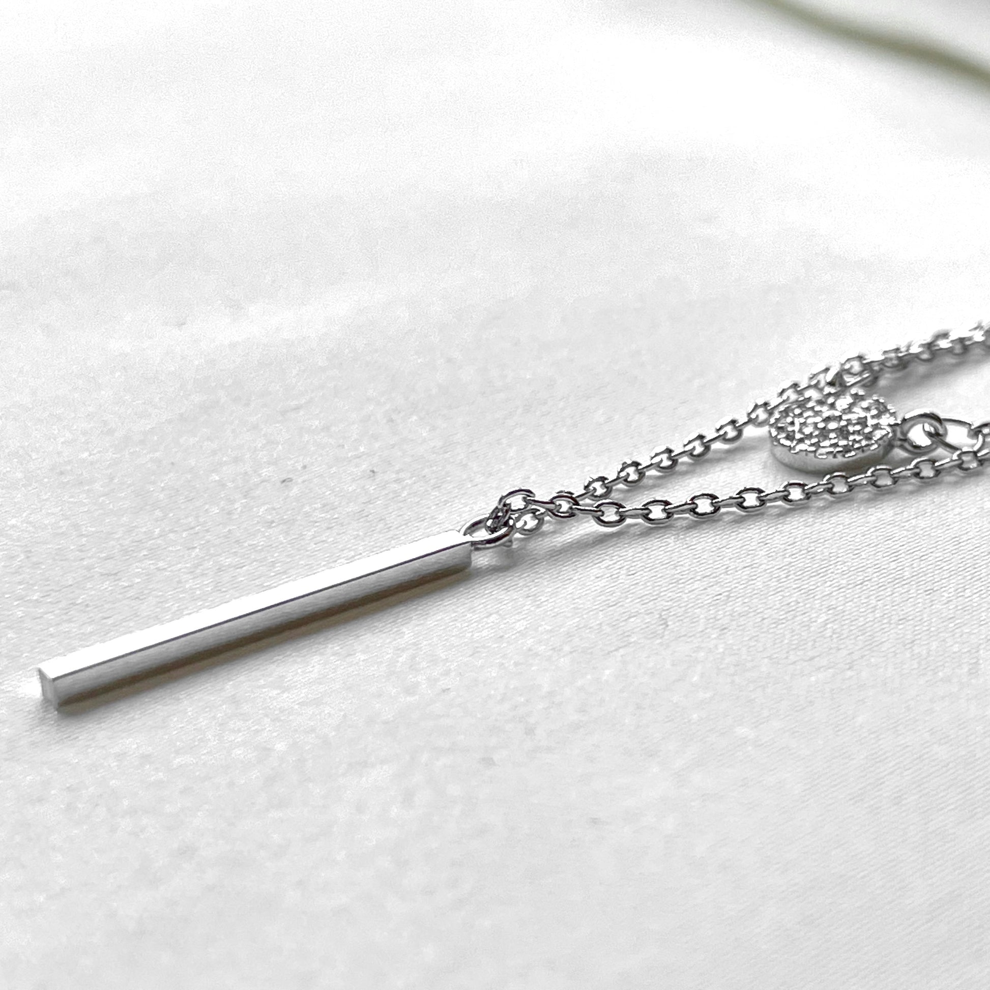 Side view of silver bar necklace on a white background