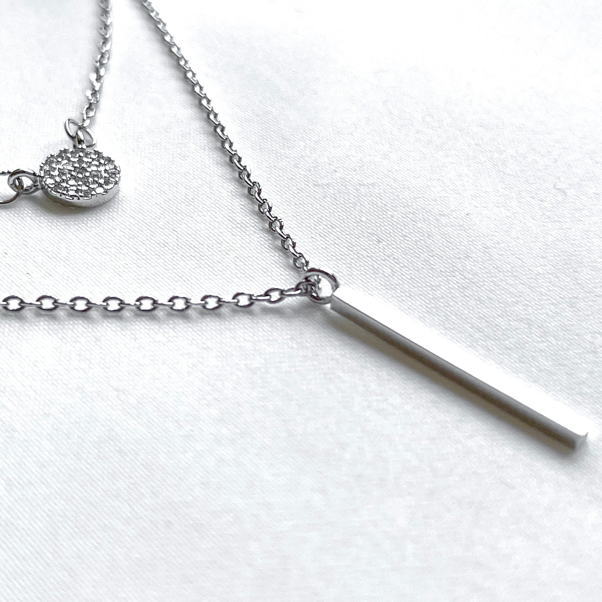 Silver necklace with a bar pendant on a white background