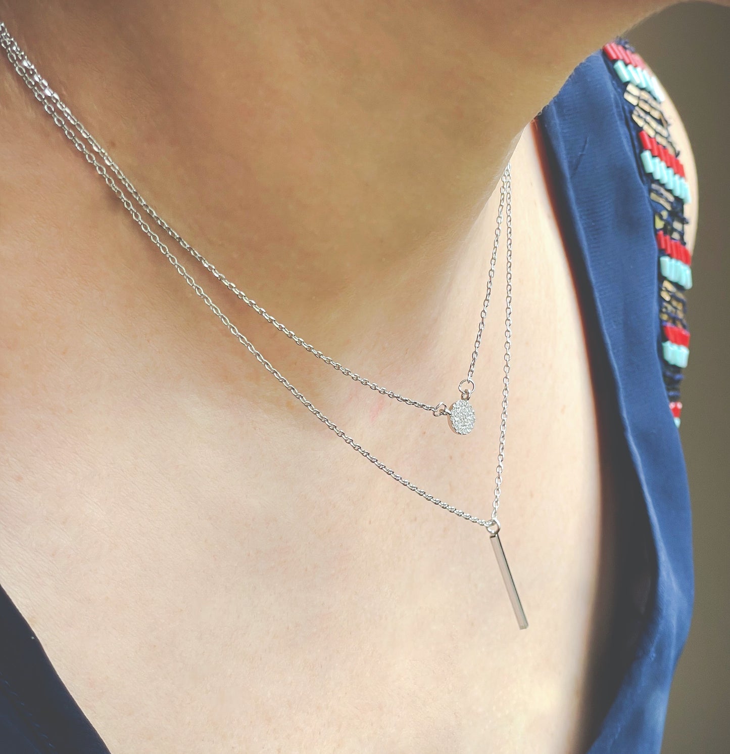 Silver necklace with a bar pendant worn by a person
