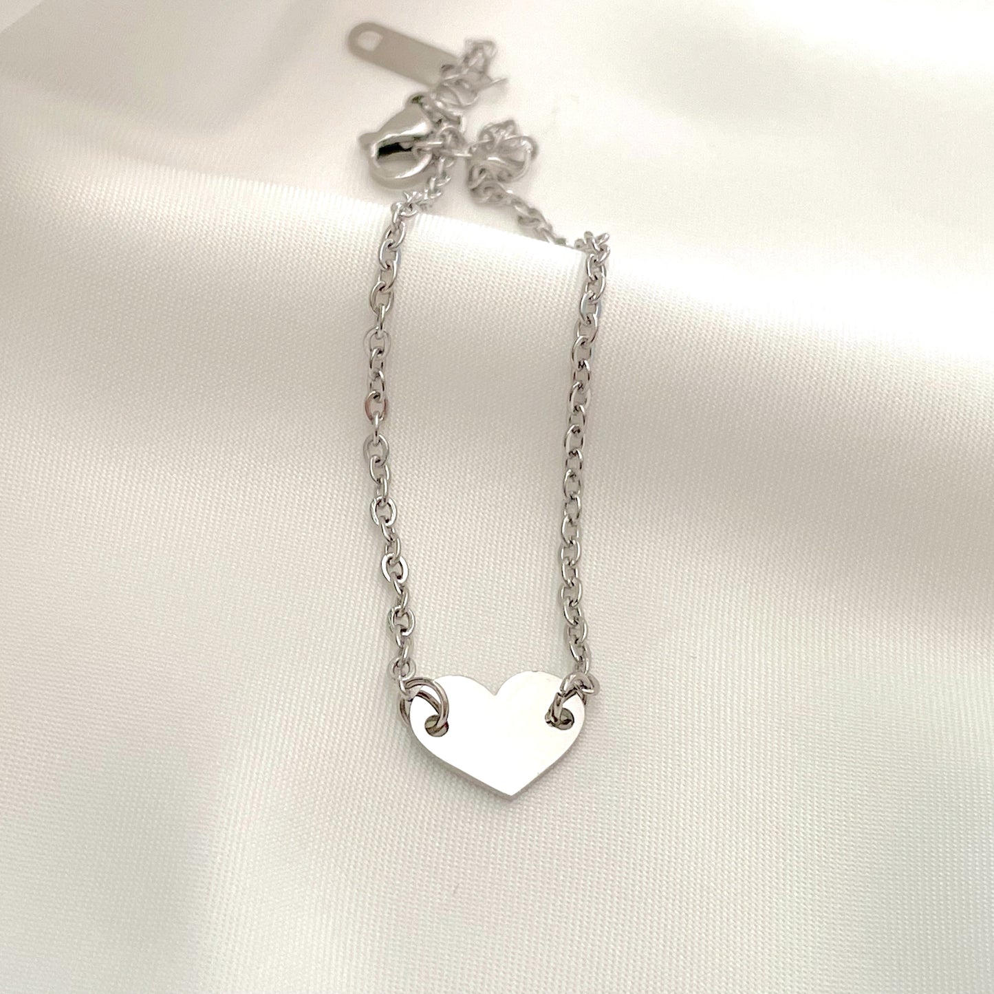 Silver heart bracelet with a delicate cable chain on a white background
