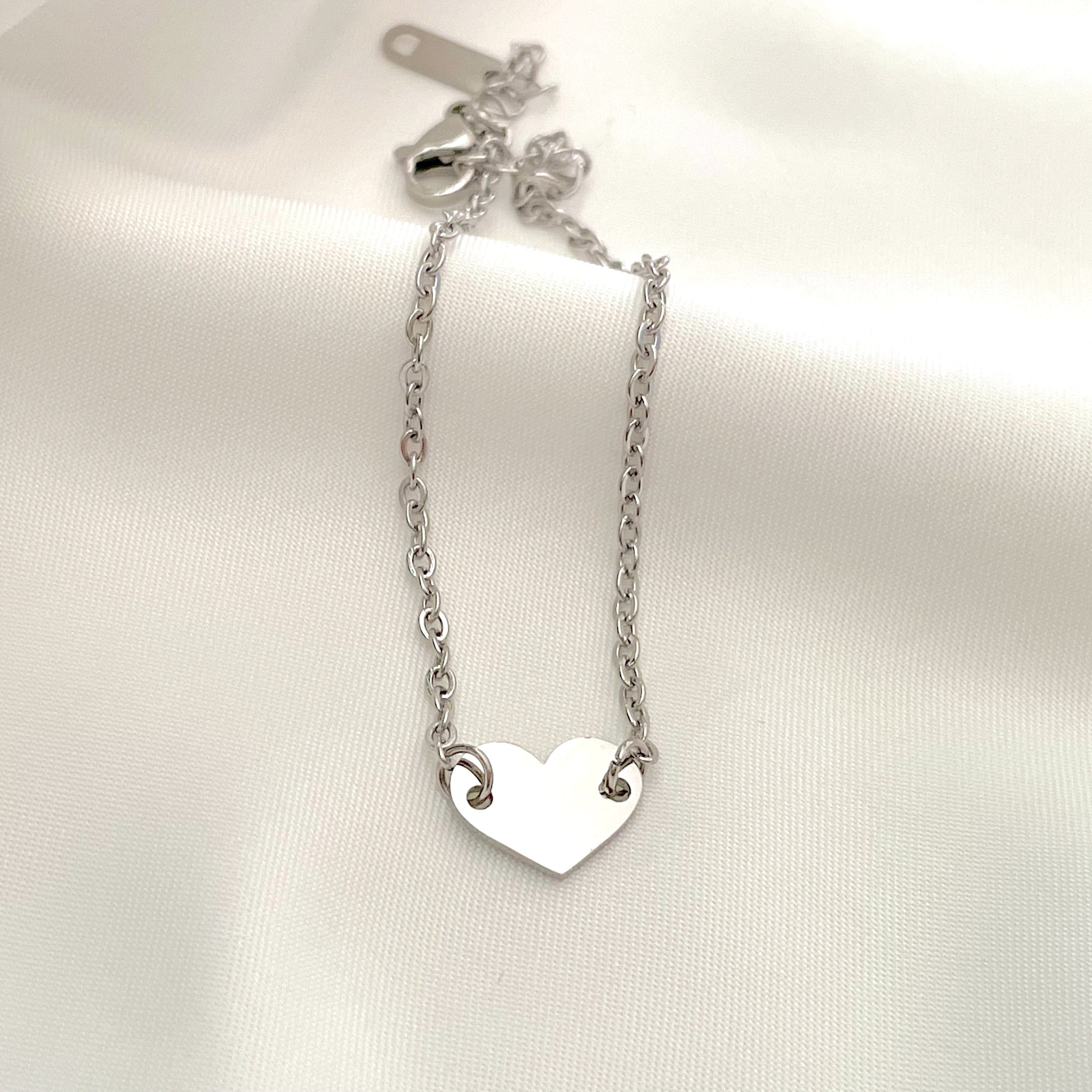 Silver heart bracelet with a delicate cable chain on a white background
