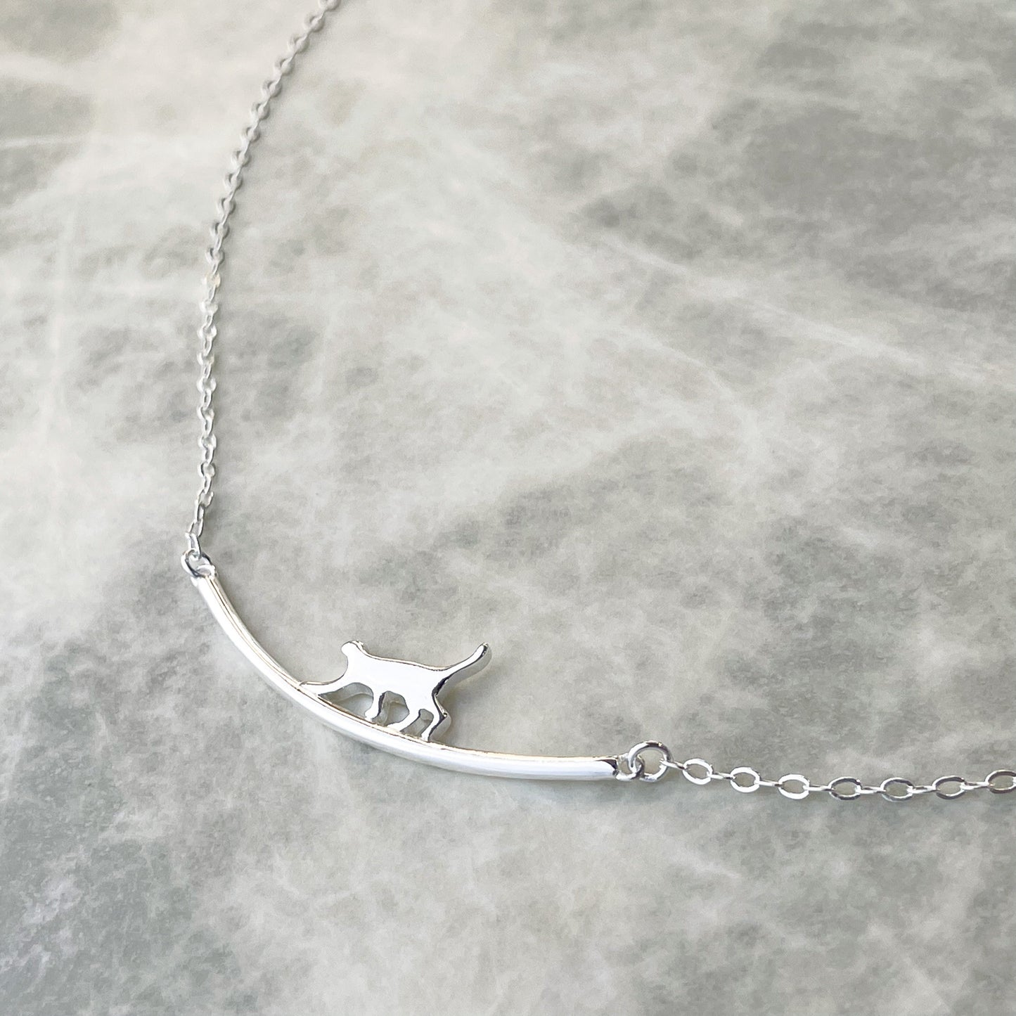 Silver necklace with a cat pendant on a light gray background