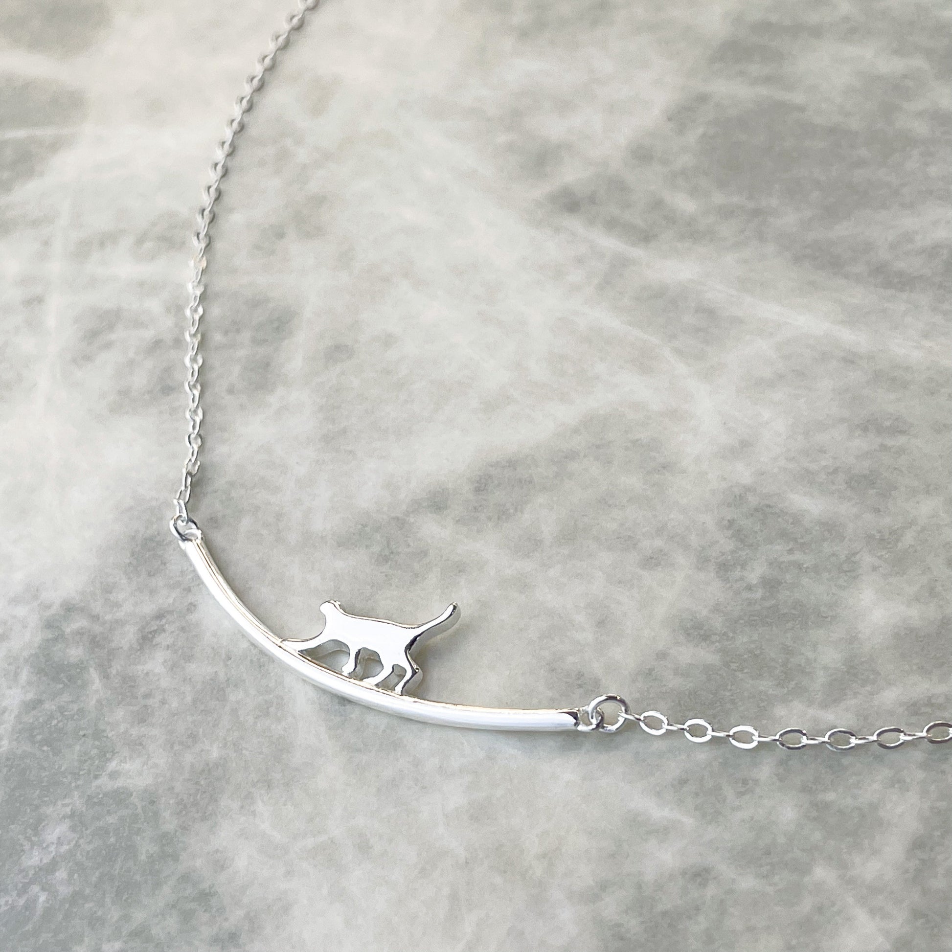 Silver necklace with a cat pendant on a light gray background