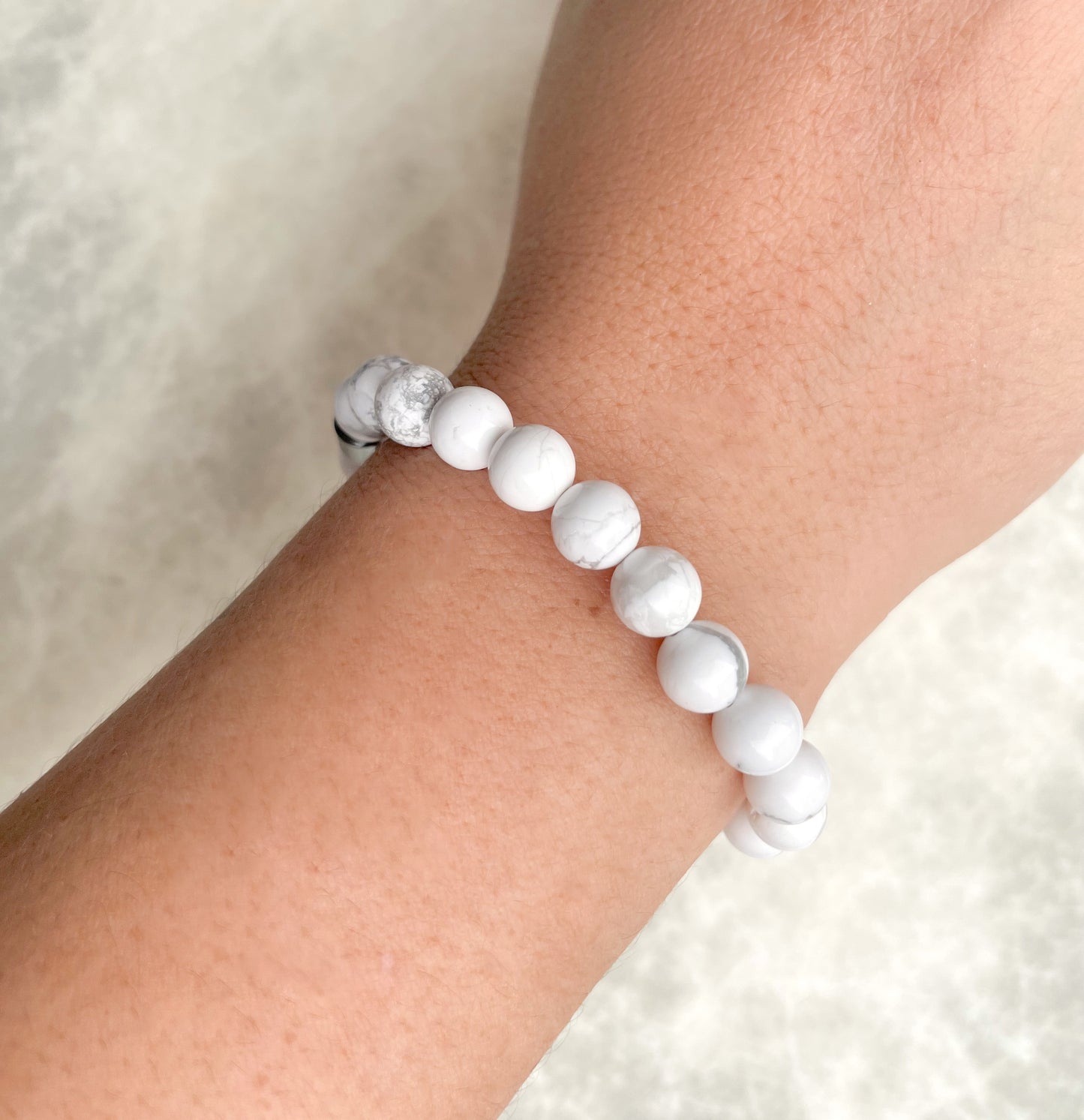 White howlite beaded bracelet on a wrist with a neutral background