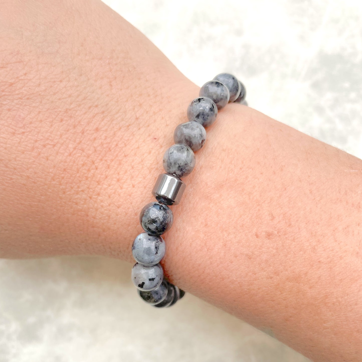 Gray natural stone bracelet on a wrist with a white background