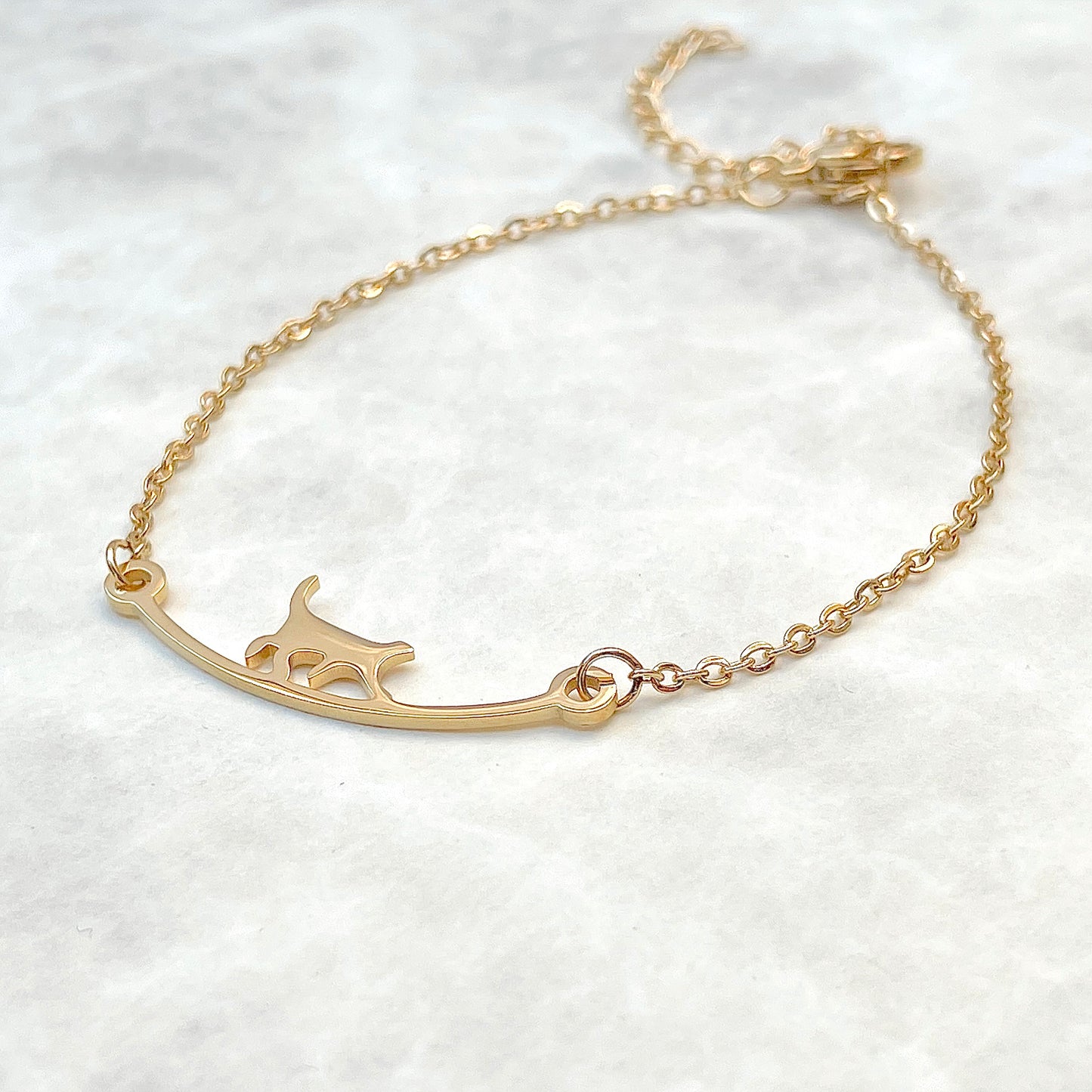 Gold curved bar cat bracelet  on a gray  background