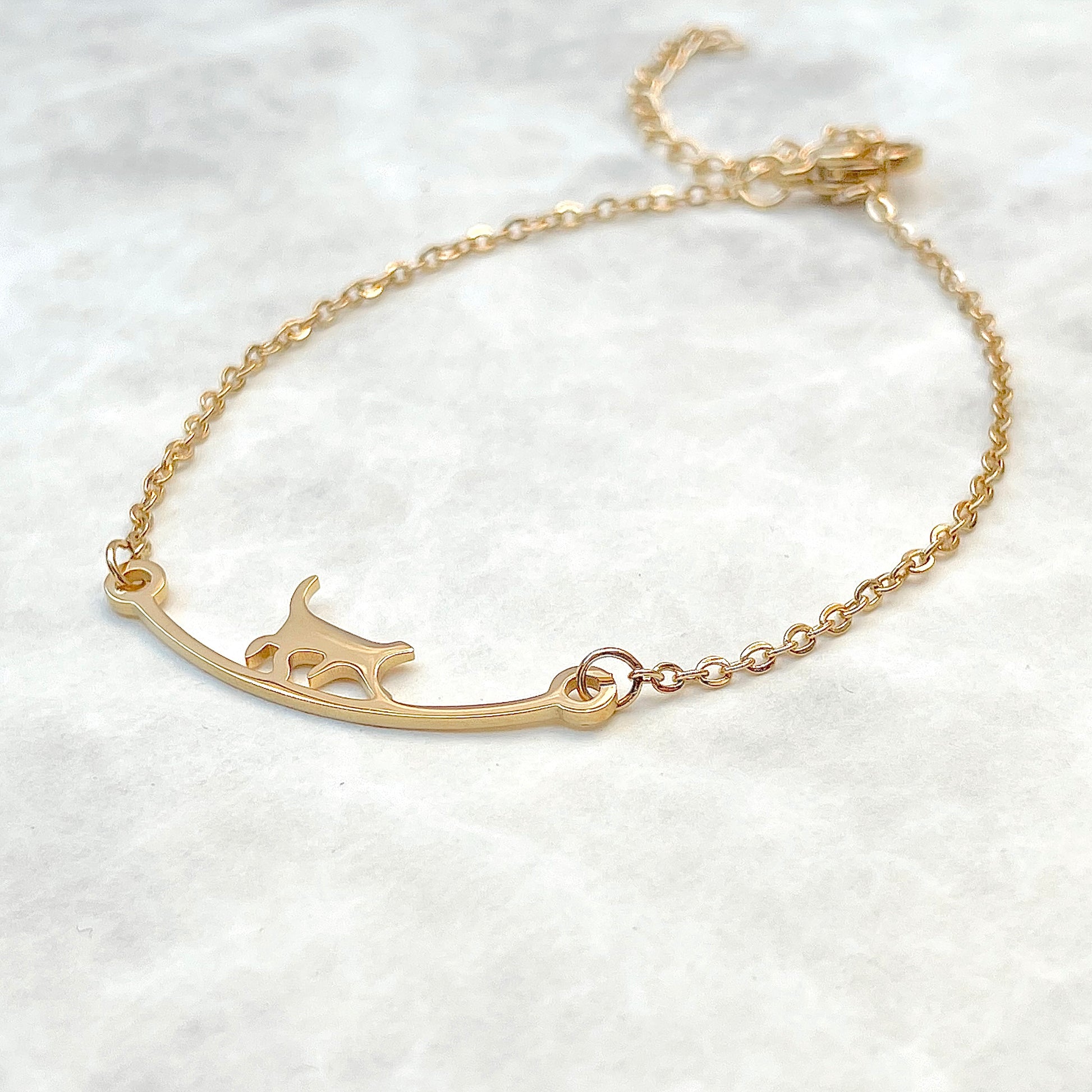 Gold curved bar cat bracelet  on a gray  background