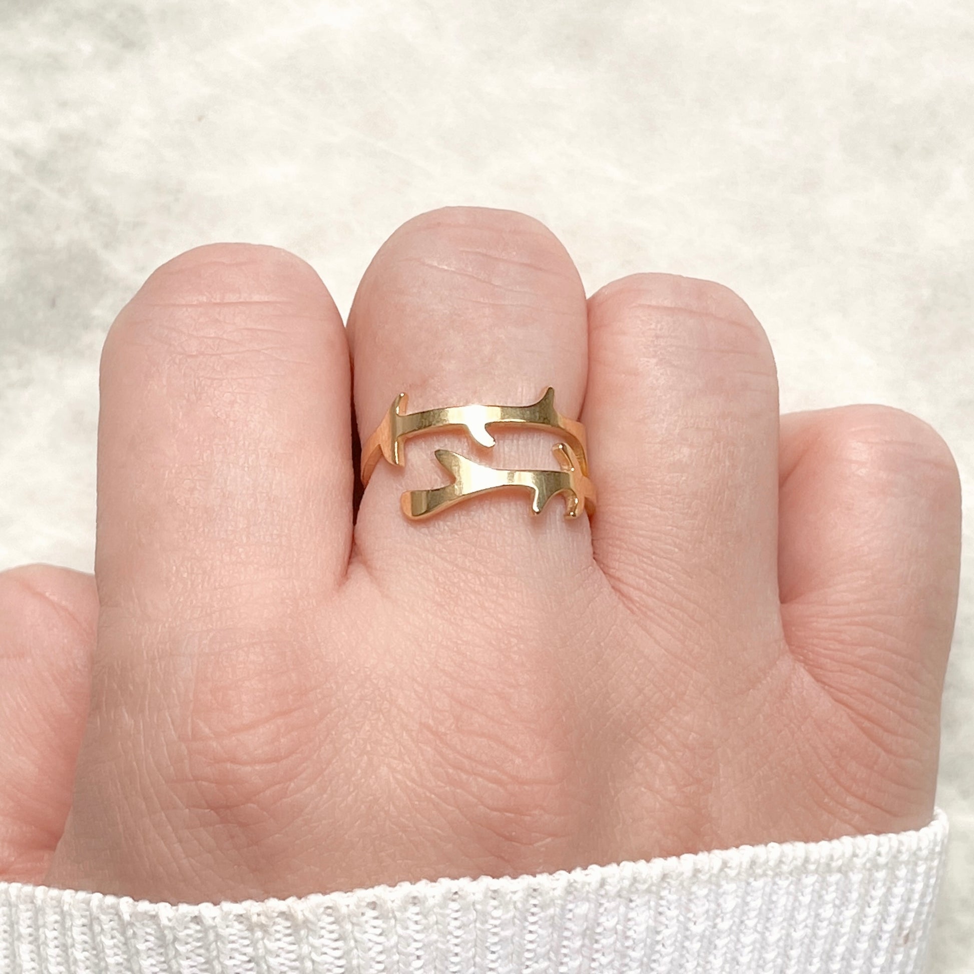 Gold  wrap ring with a branch design on a finger against a white background