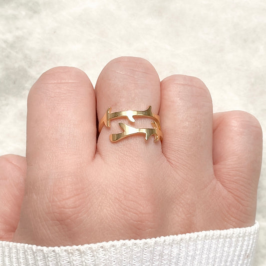 Gold  wrap ring with a branch design on a finger against a white background