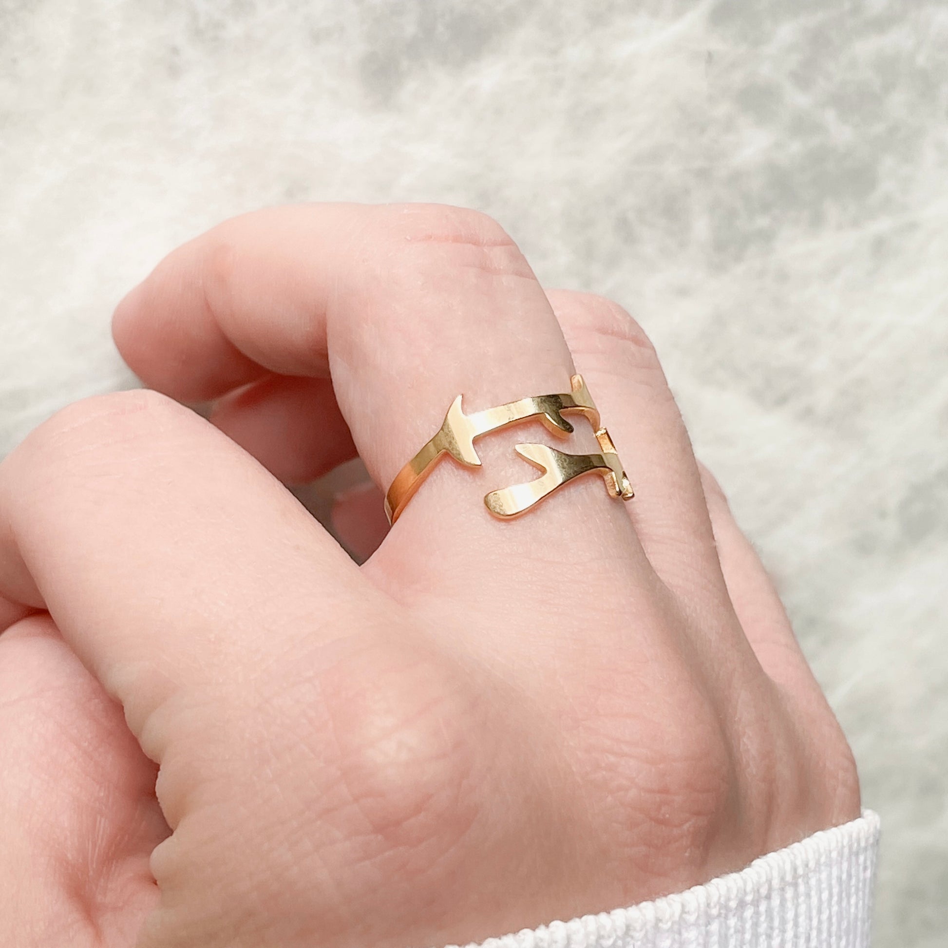 Adjustable layered Gold ring on a person's finger against a soft background