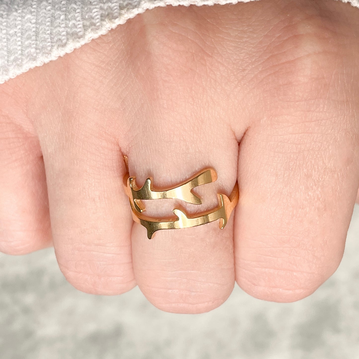 Close-up view of sculptural gold ring on a finger with a blurred background