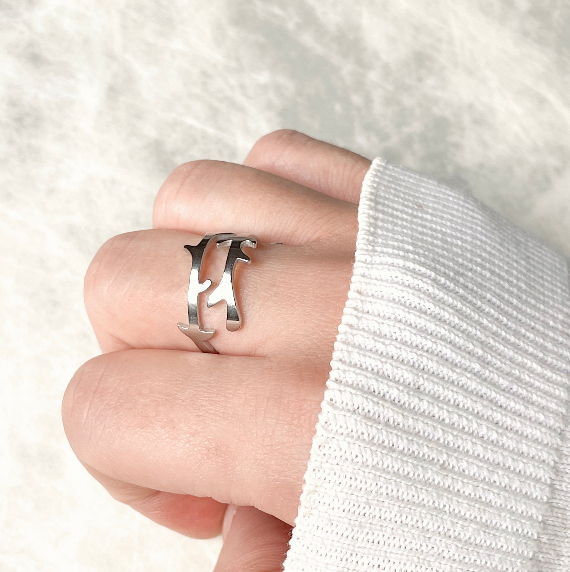Silver ring with a branch design worn on a finger against a white background