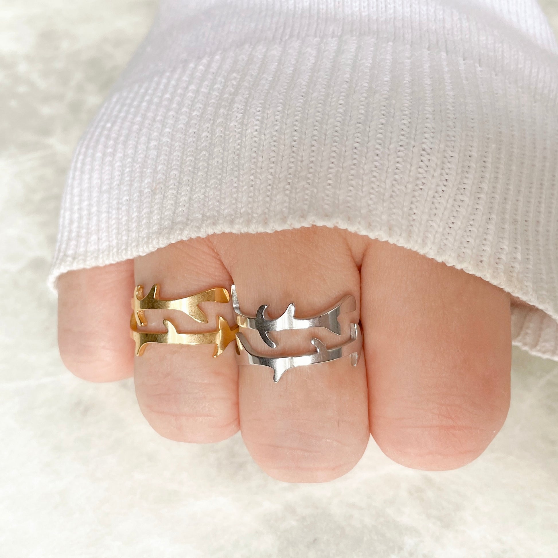 Two rings, one gold and one silver, on a finger against a white background.