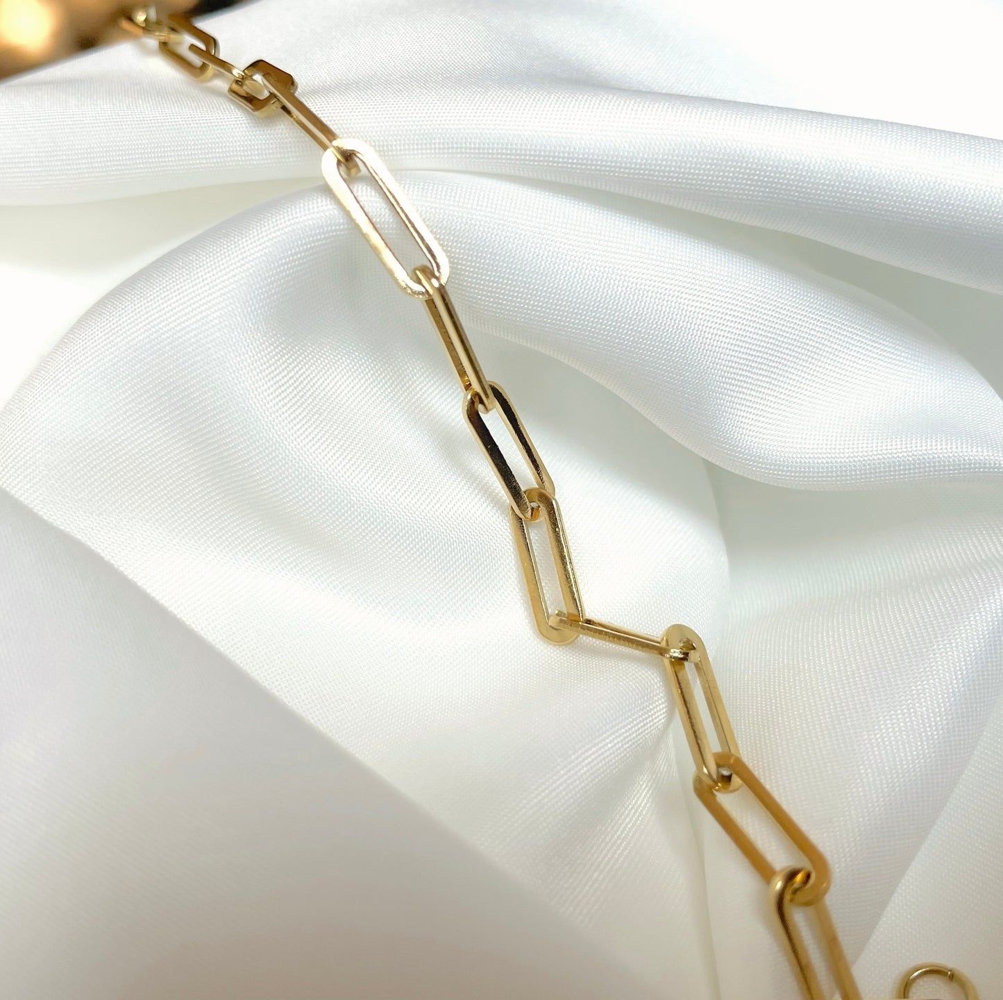 Gold chain necklace on a white satin background